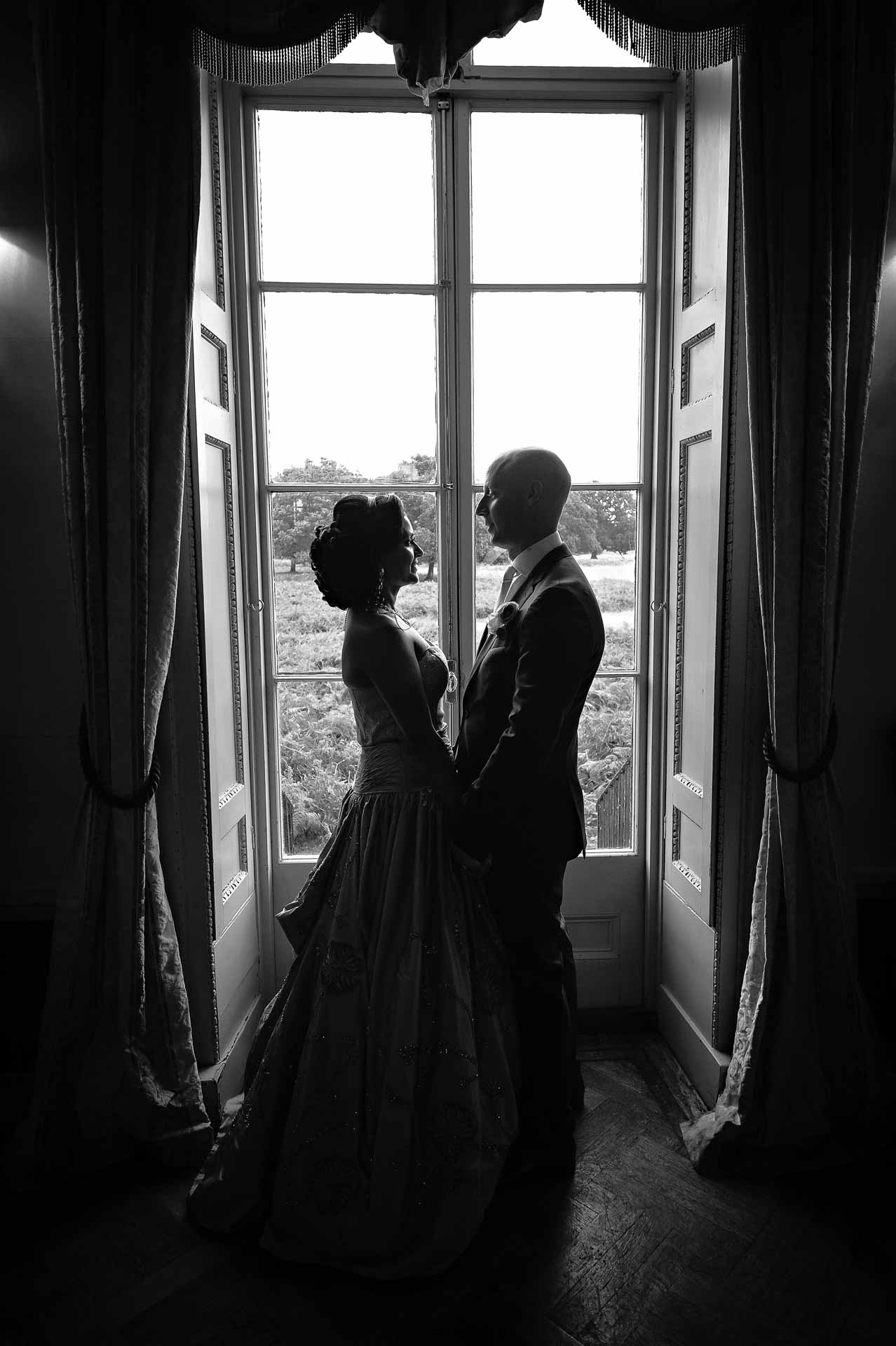 Married couple in silhouette at wedding in window of Hampton Court House