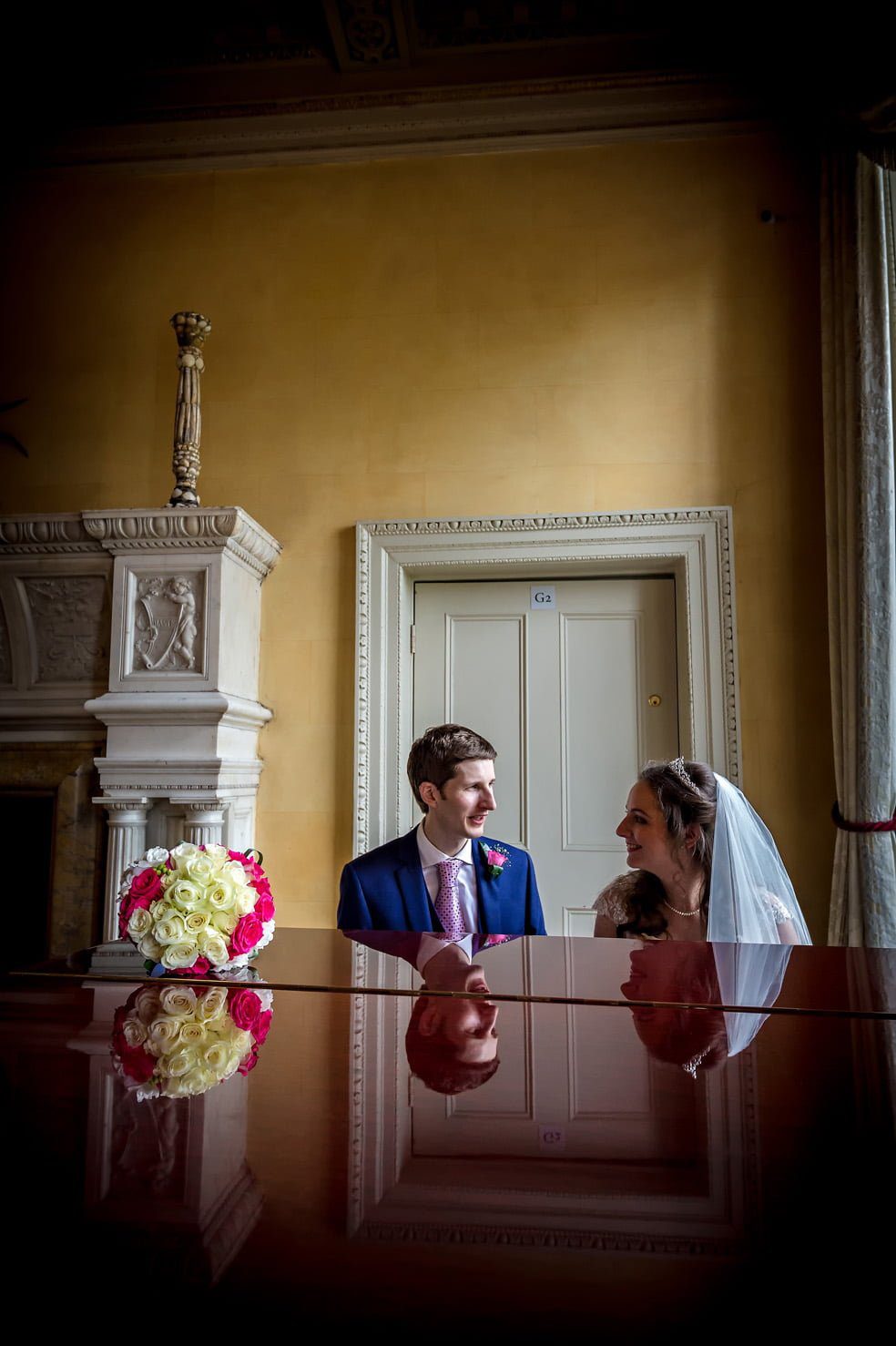 Newly-weds pose with piano in main hall of Hampton Court House