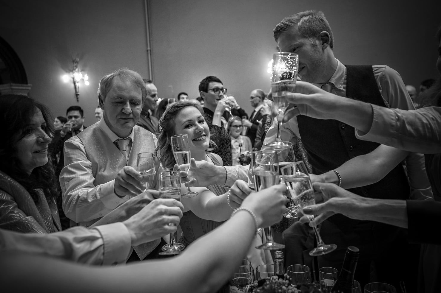 Wedding guests toasting couple in black and white