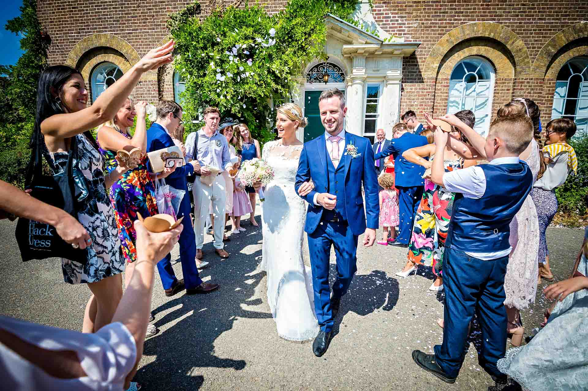 Couple leaving wedding at Morden Park House with guests throwing confetti