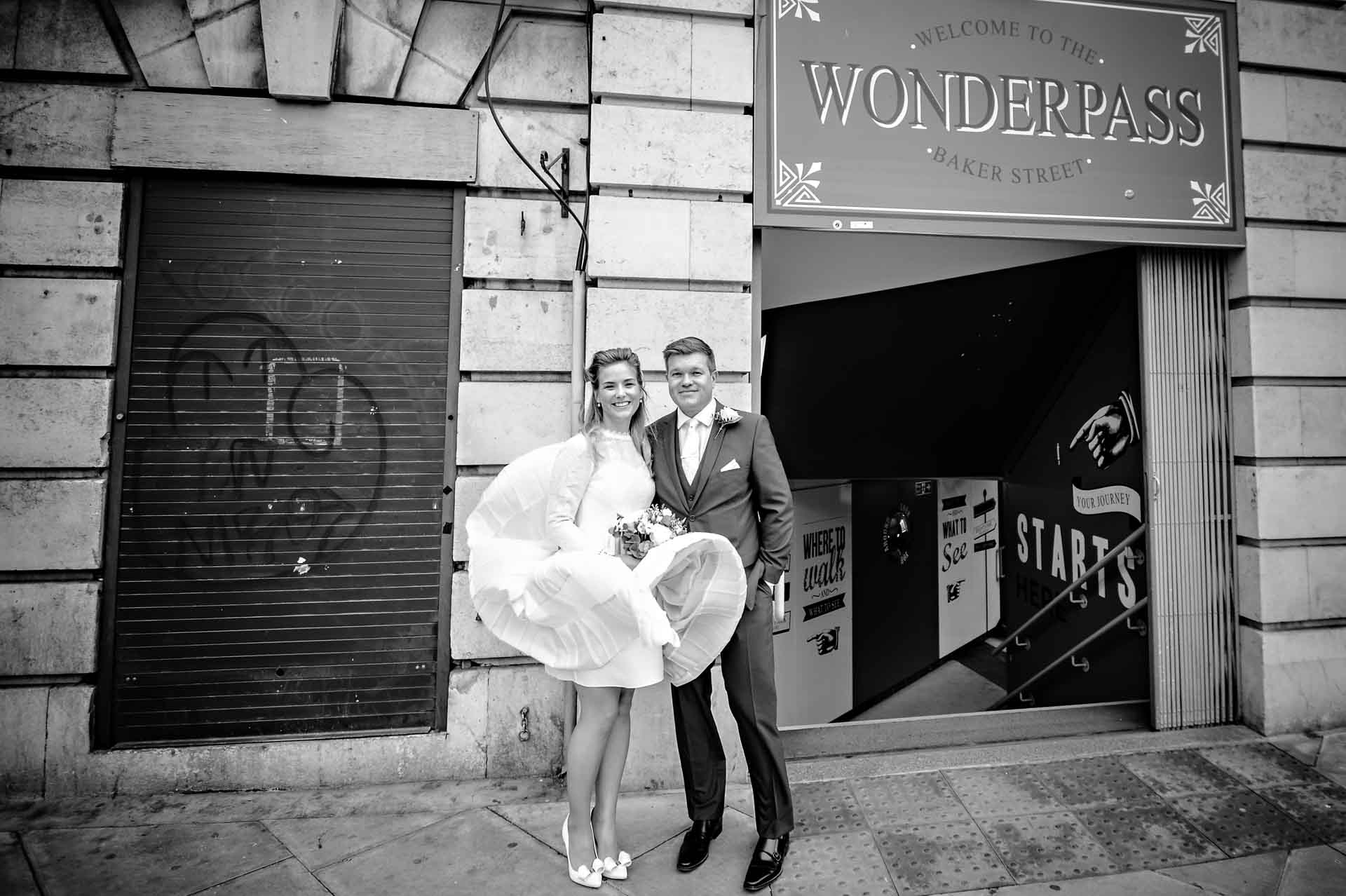 Wedding couple outside Baker Street Station - bride with dress flying up