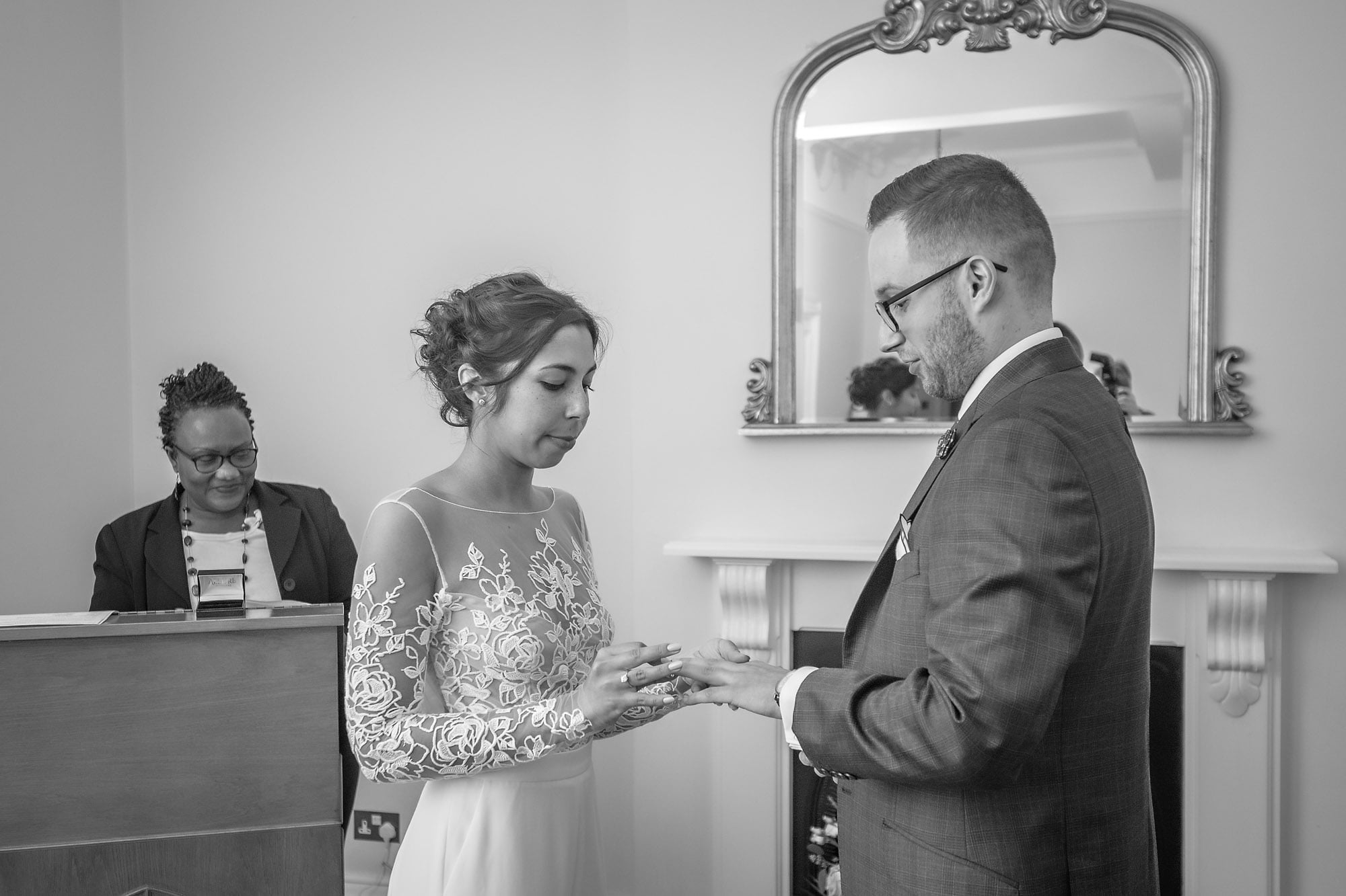 The bride places the ring on the finger of the groom at a register office wedding in Greenwich