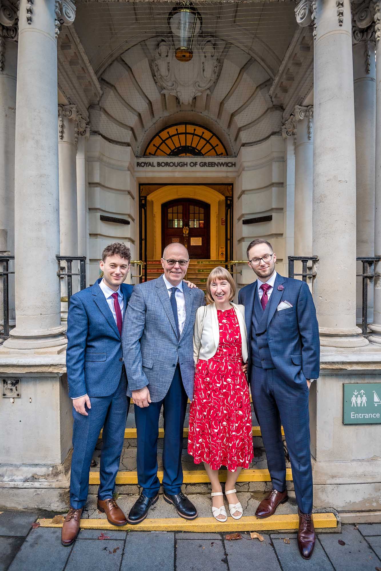 Groom poses on steps of Woolwich Town Hall with brother and parents