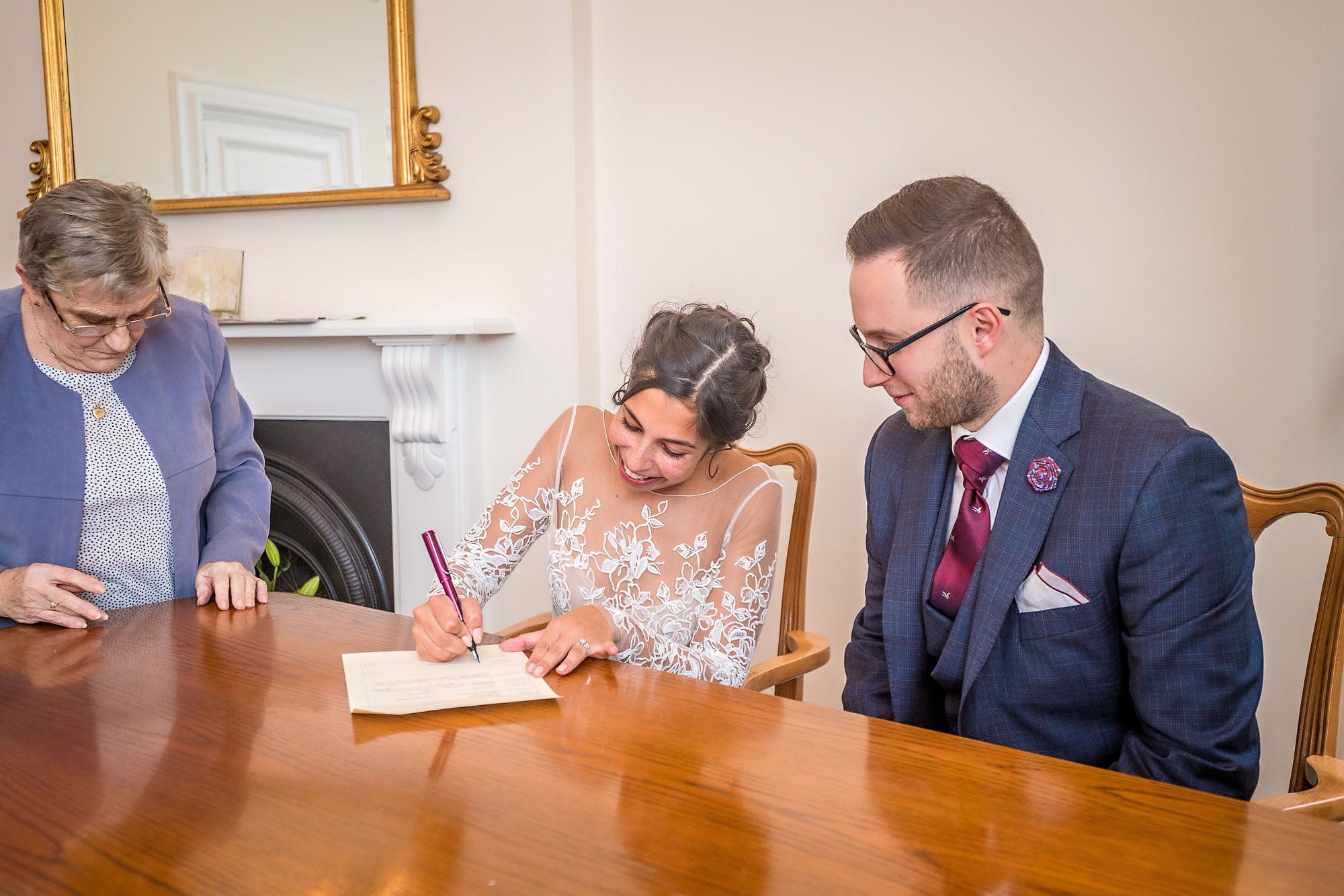 Bride smiling and signing her wedding schedule at Woolwich Town Hall