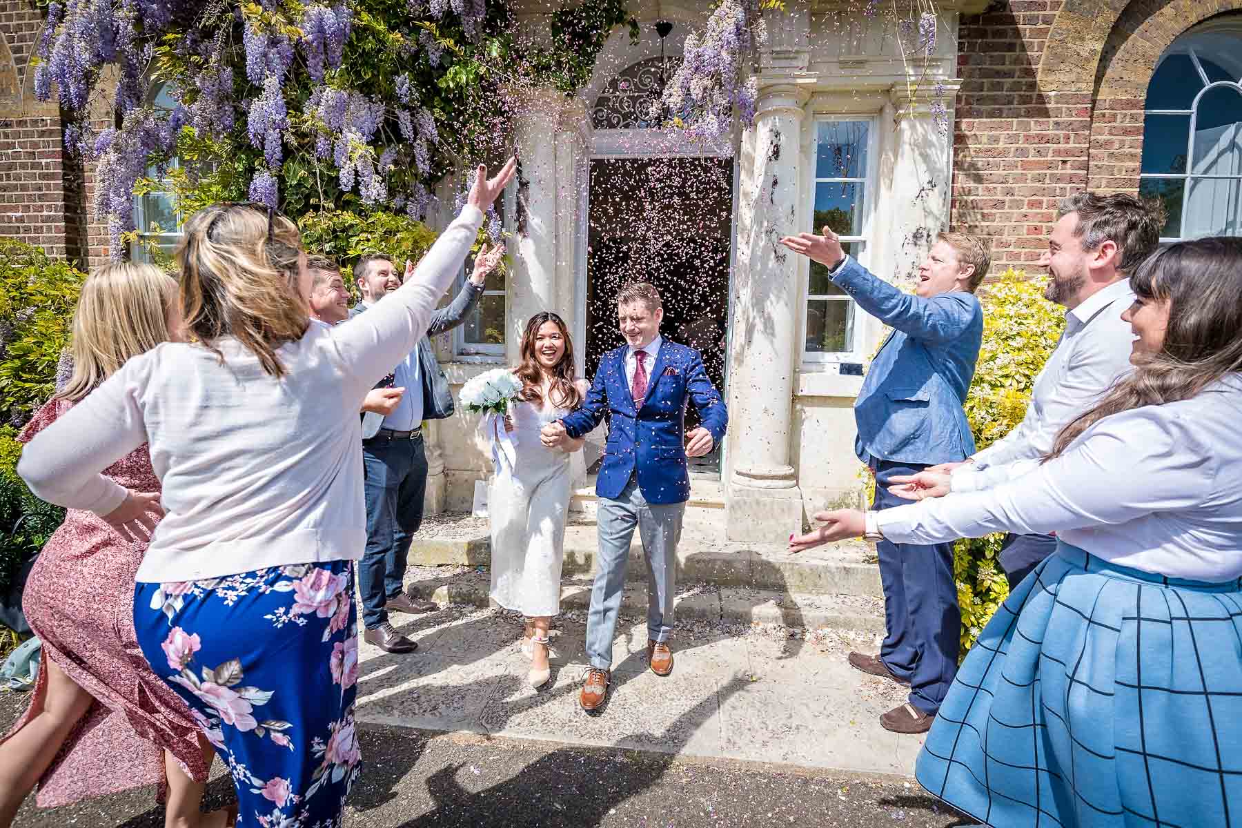 Guests dynamically throwing confetti over couple at Merton Register Office wedding