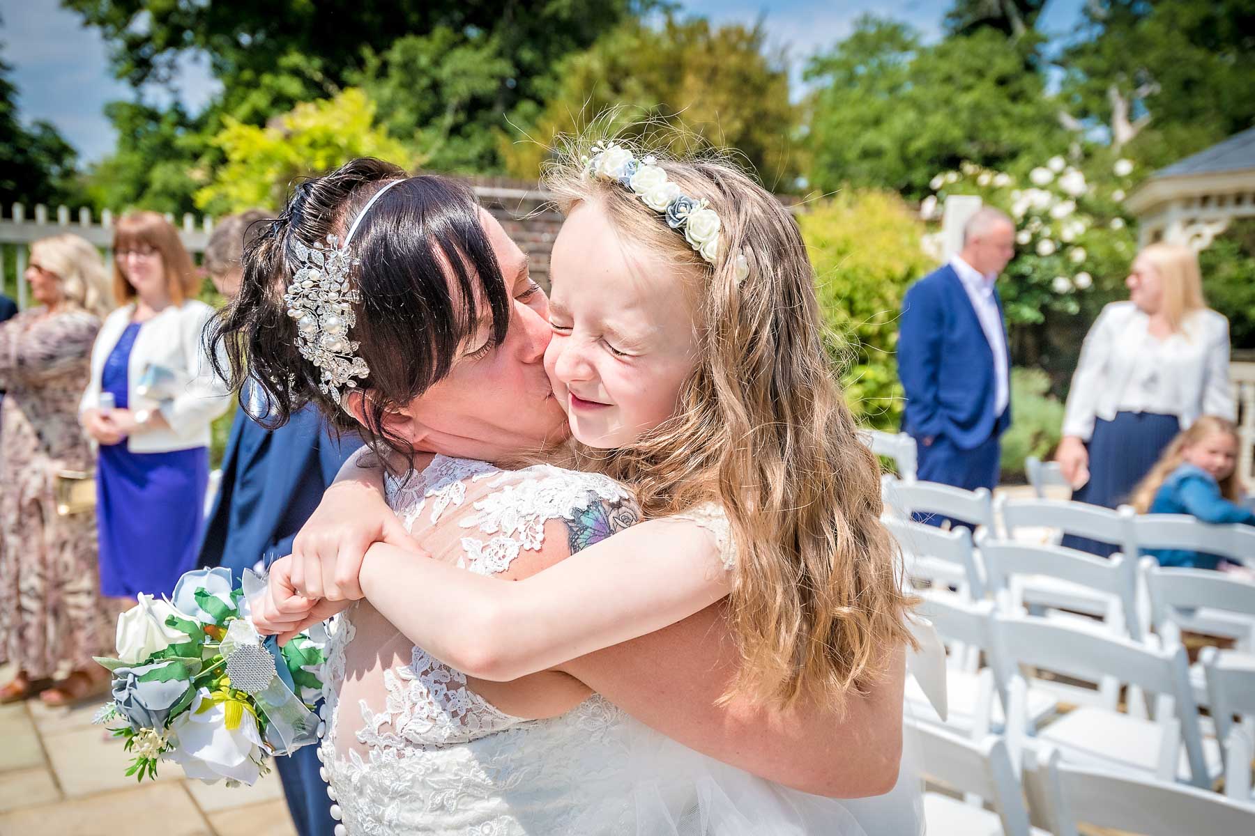 Little girl hugging the bride in the sunshine outside Morden Park House in South London