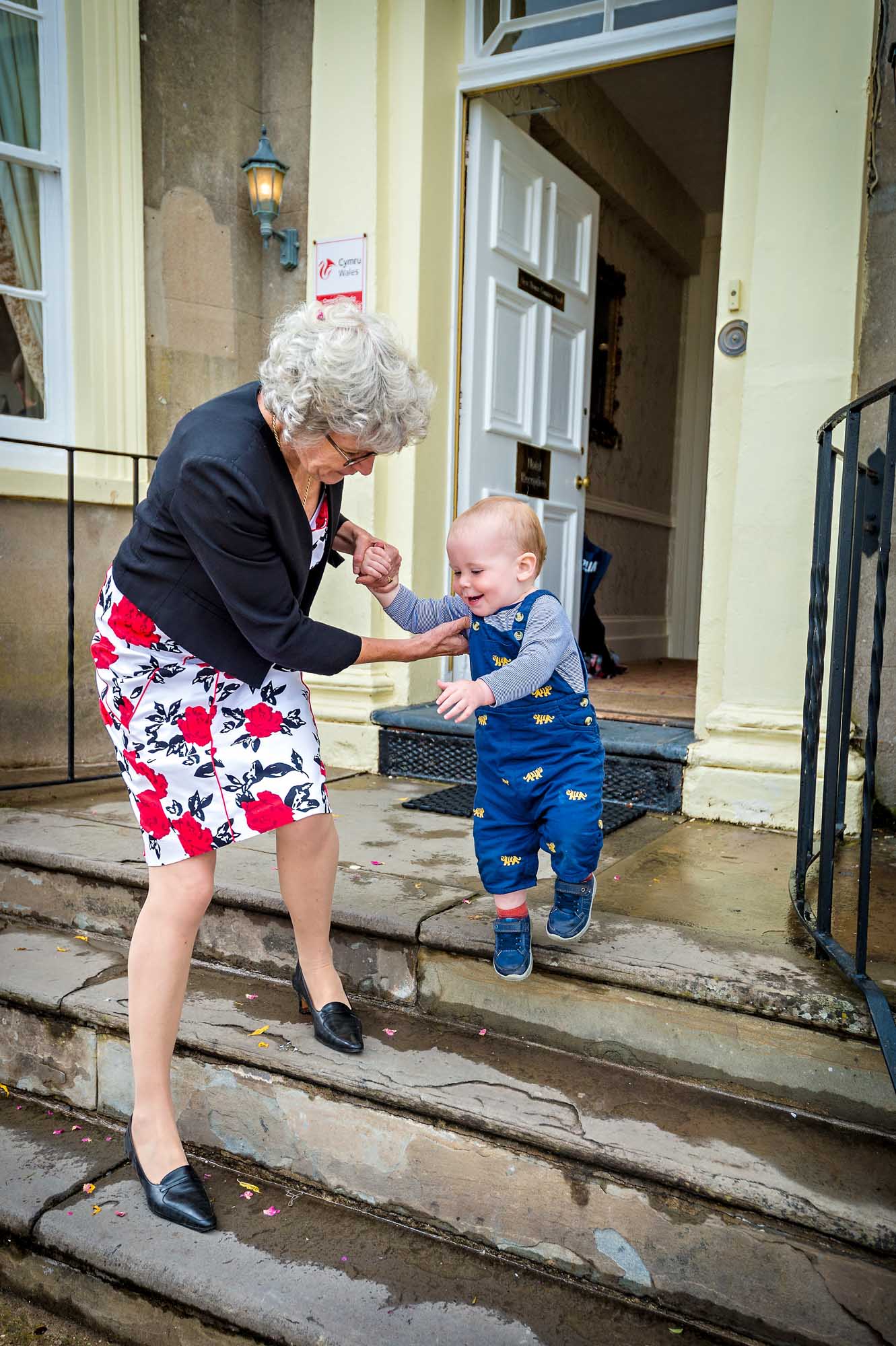 Grinning toddler helped down hotel steps at Cardiff wedding