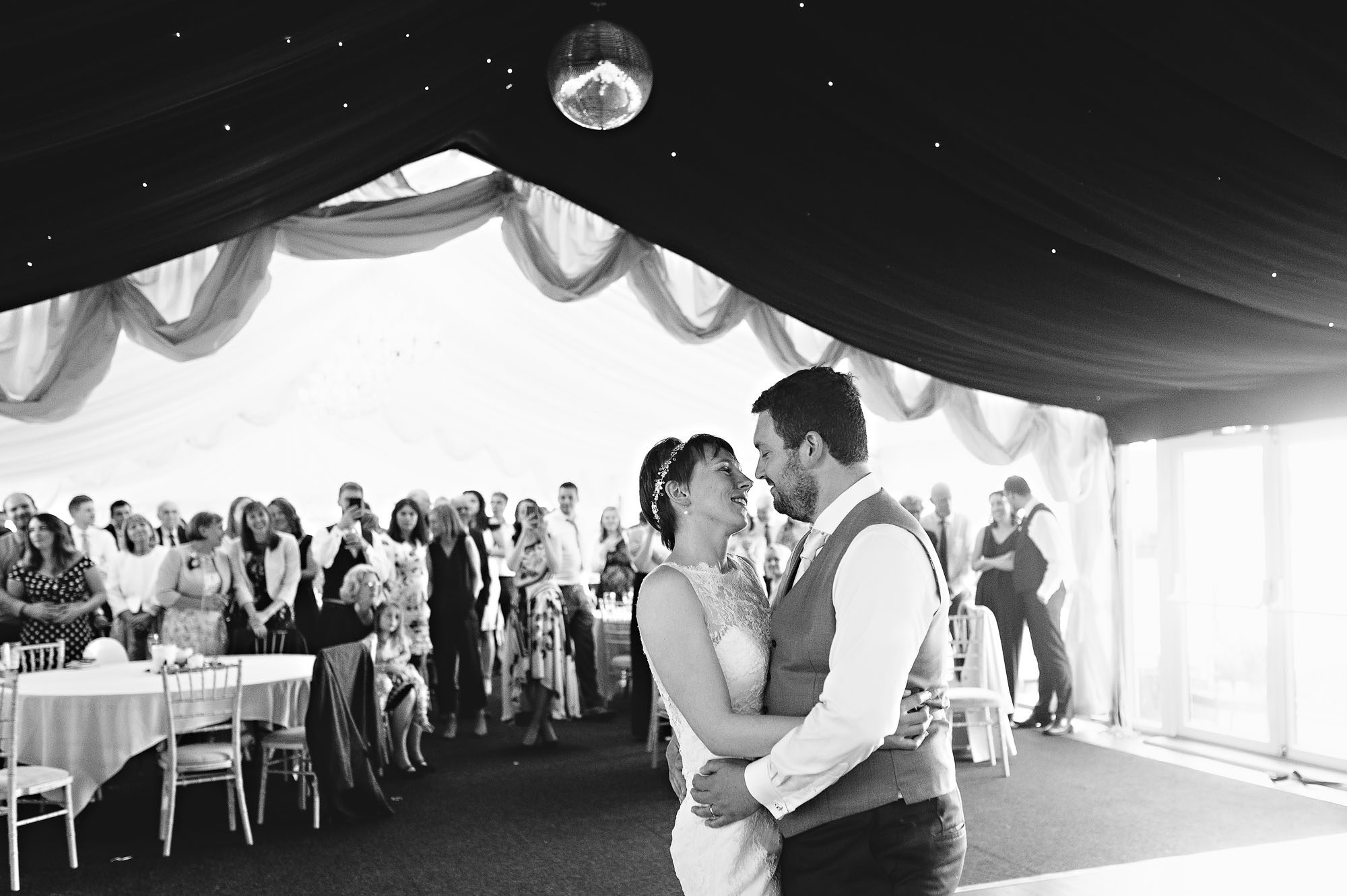 Couple gazing into each others eyes during the first dance with guests watching in background