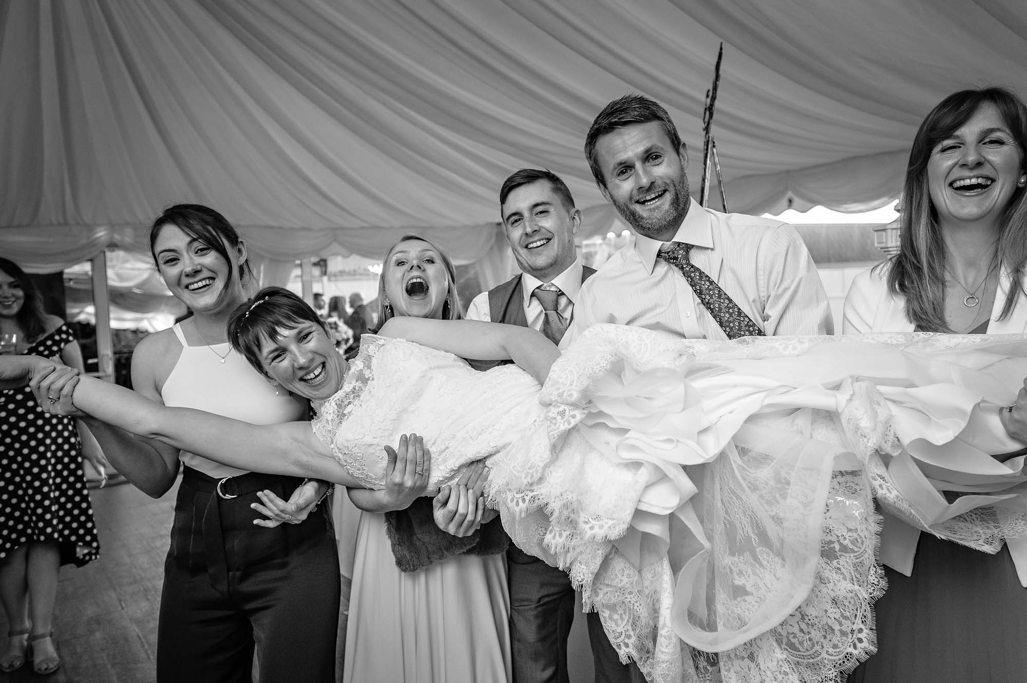 Guests holding bride lying down at Welsh wedding