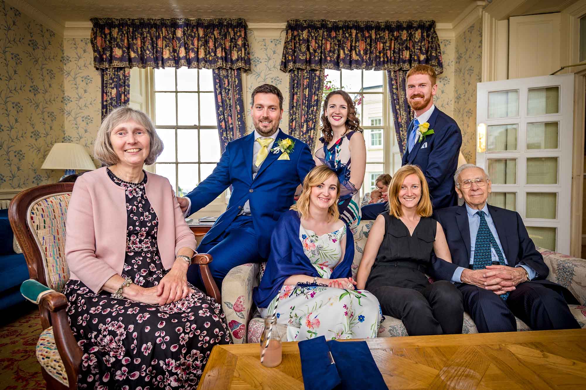 Groom posing with six wedding guests in lounge of New House Country Hotel