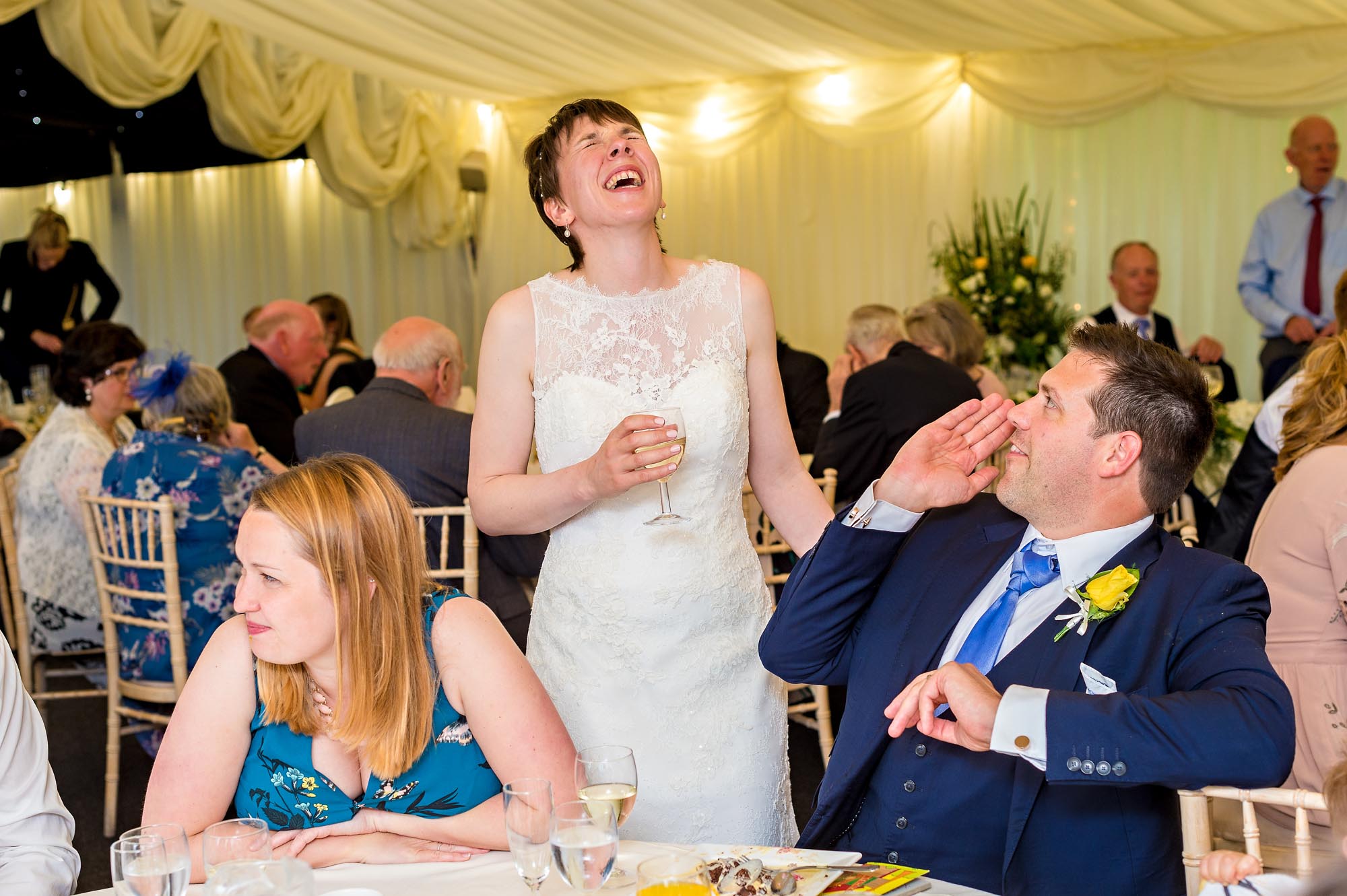 As the bride circulates during the wedding reception, she laughs with a guest