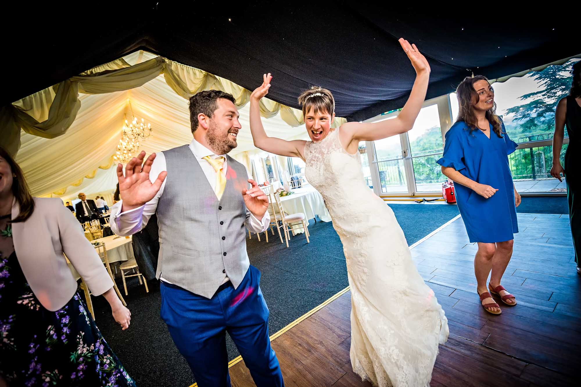 Couple dancing with guests in marquee