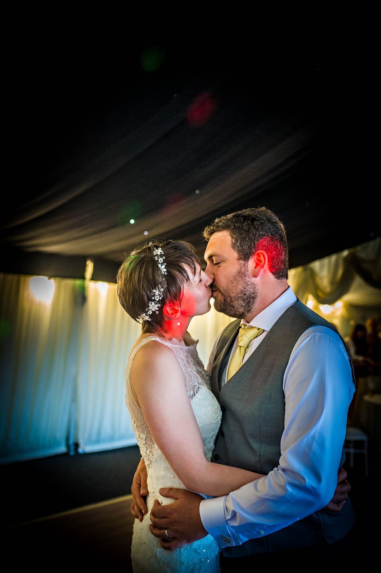 The couple kiss during first dance in marquee