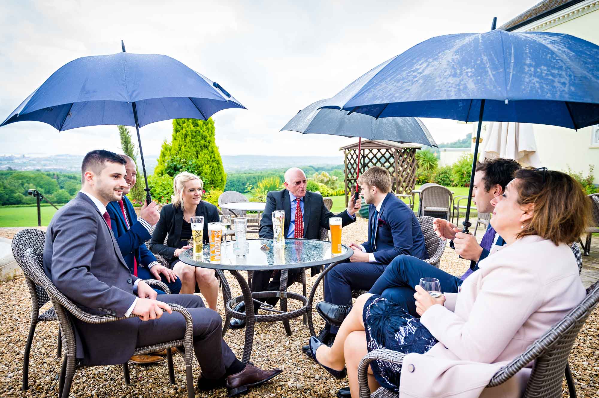 Wedding guests sitting under umbrellas at table outside New House Country Hotel