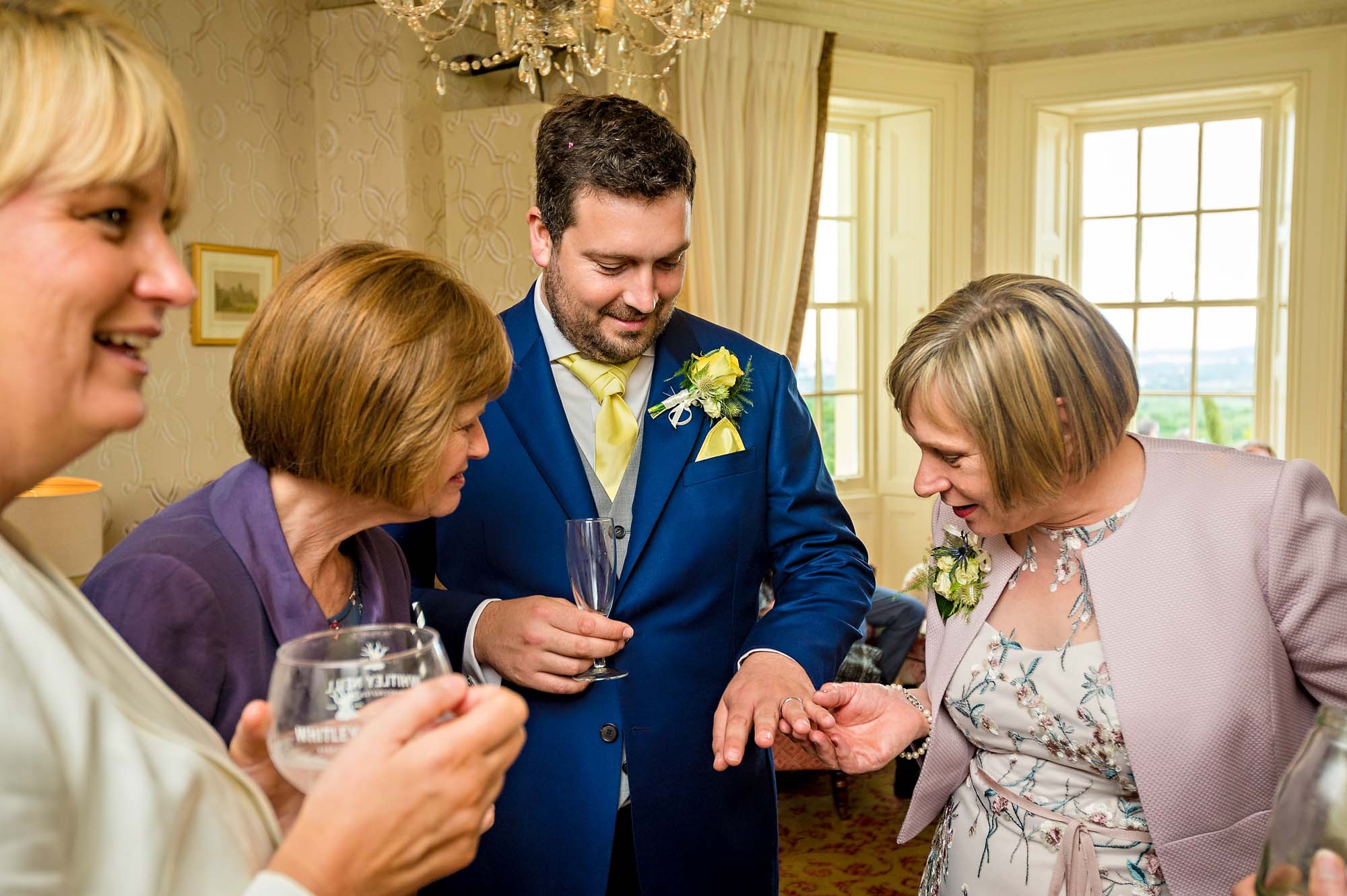Bride's mum admiring groom's wedding ring with other guests