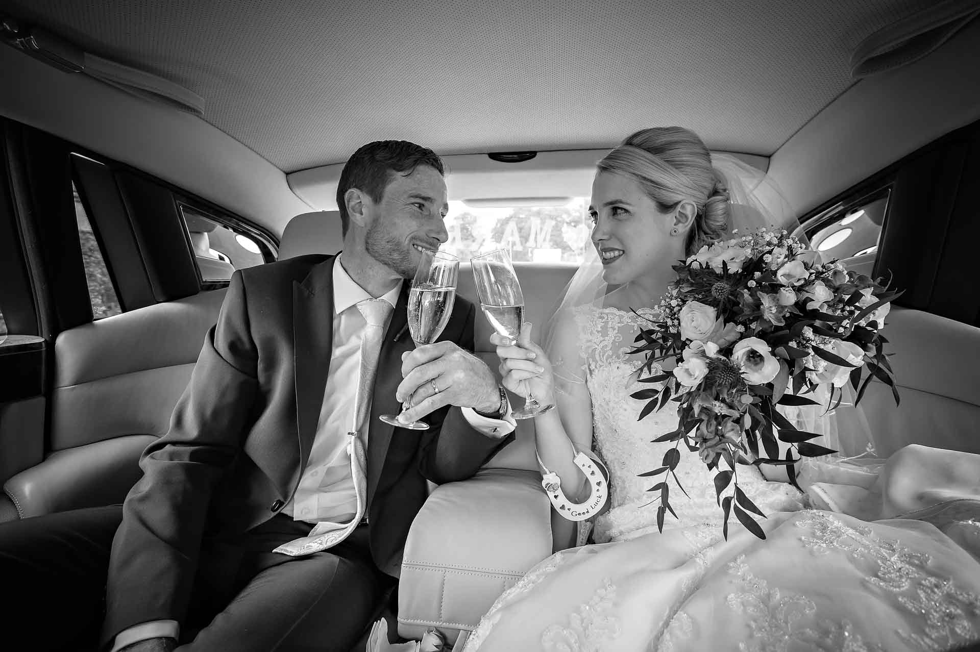 Bride and Groom Toasting in Back of Wedding Car