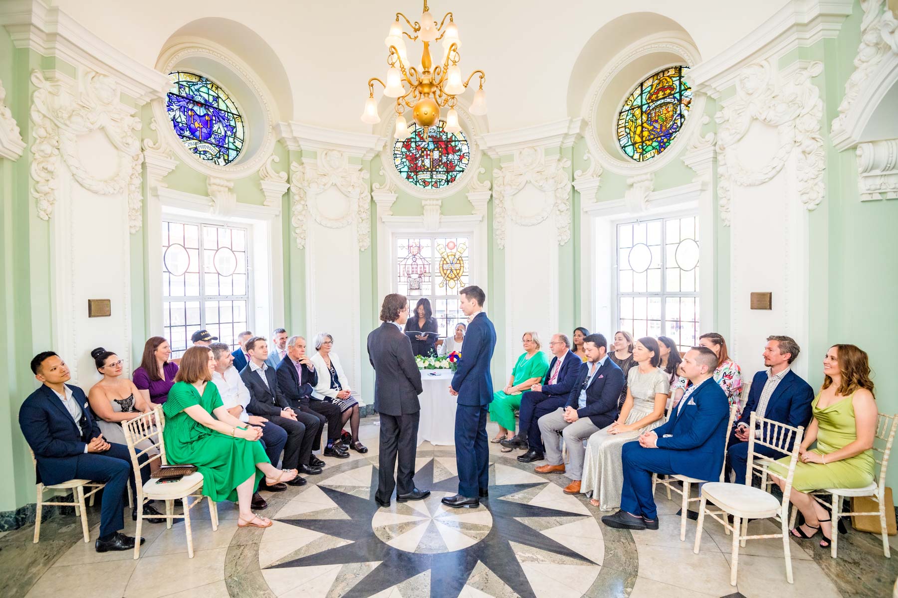 Grooms standing with each other in front of their guests in the Circular Hall at Lambeth