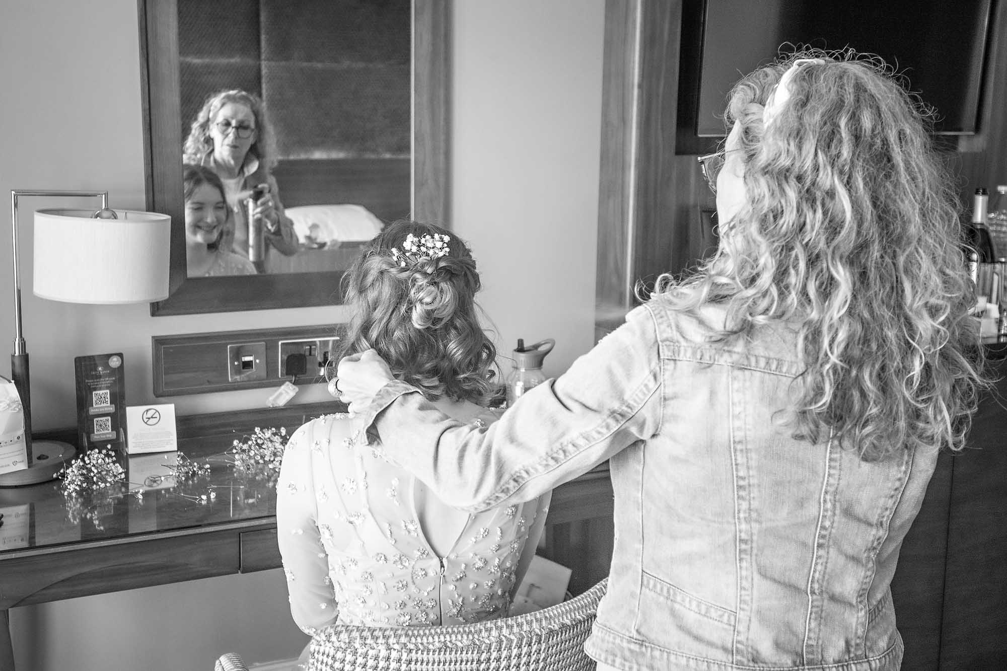 Hair and make-up artist spraying the bride's hair in a hotel room at Celtic Manor Resort wedding preparations