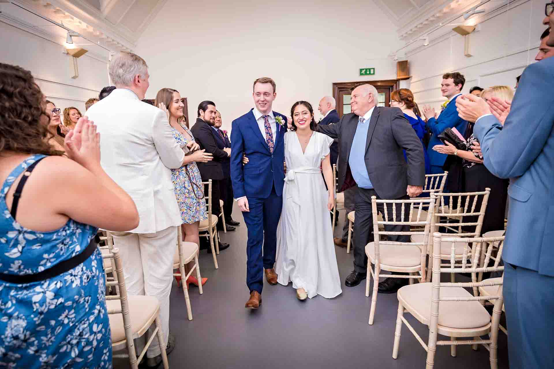 Newly-weds walk down the aisle at Fulham Library after their ceremony