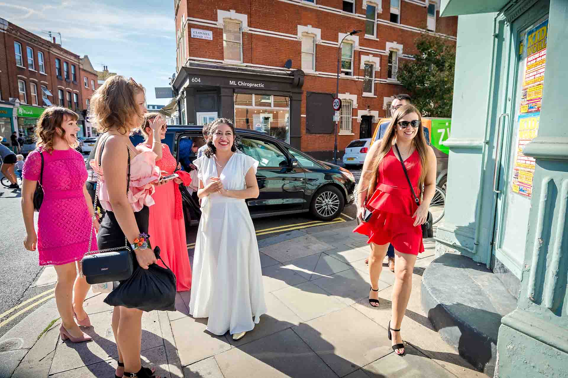 Bride arrives with bridal party on Fulham Road for wedding