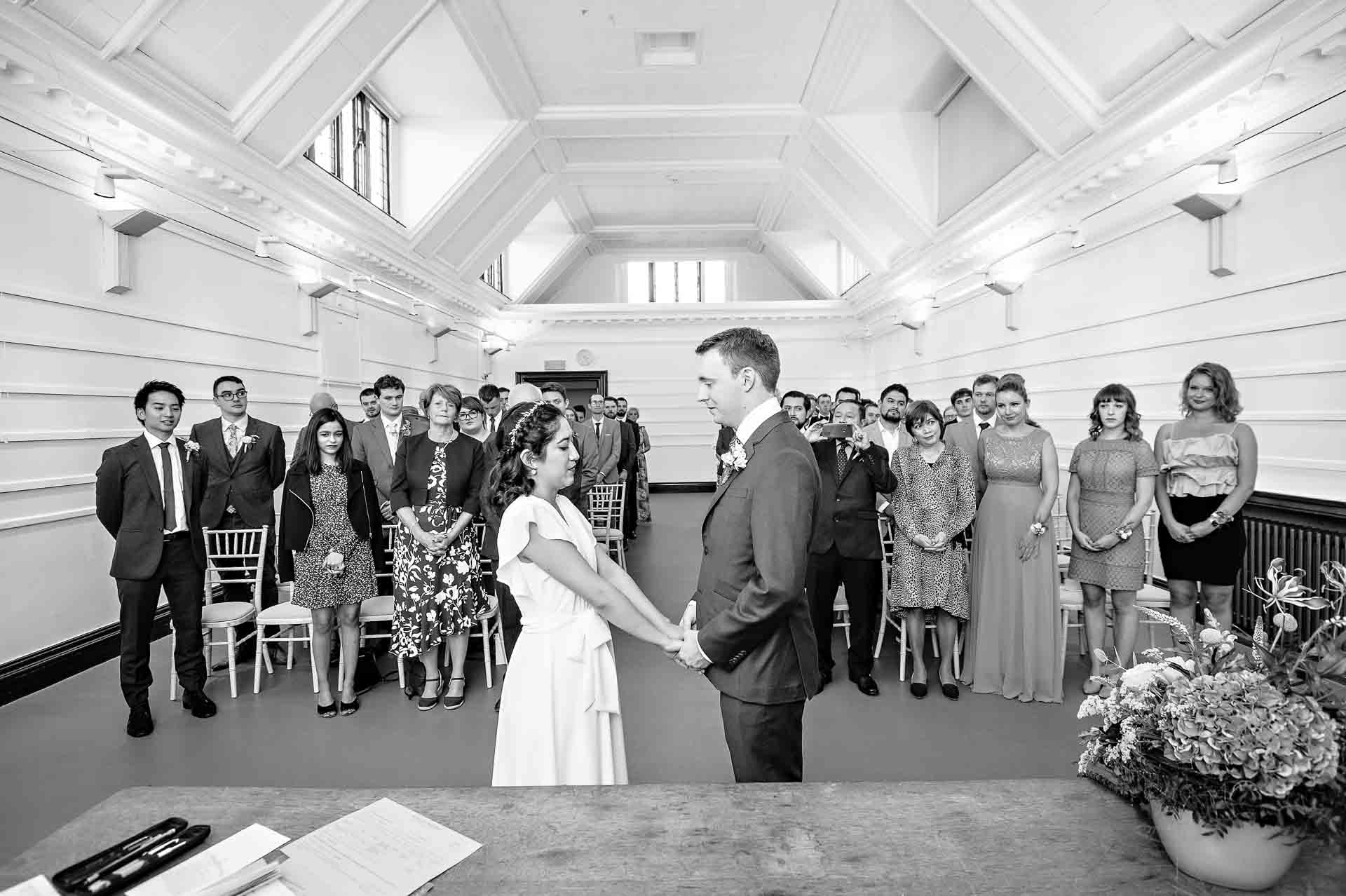 Bride and Groom holding hands with guests in background at Fulham Library wedding