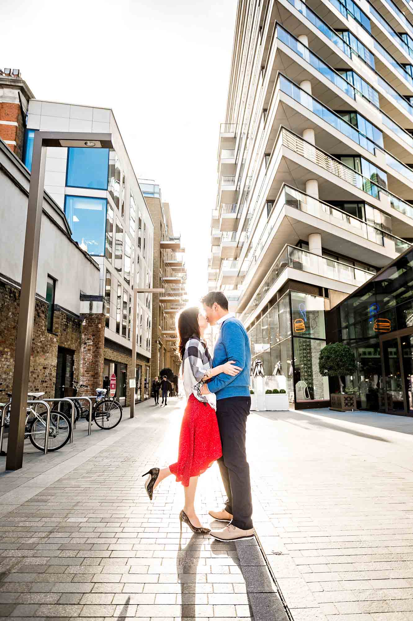 Couple kissing in London street with appartment block and the sun in the background