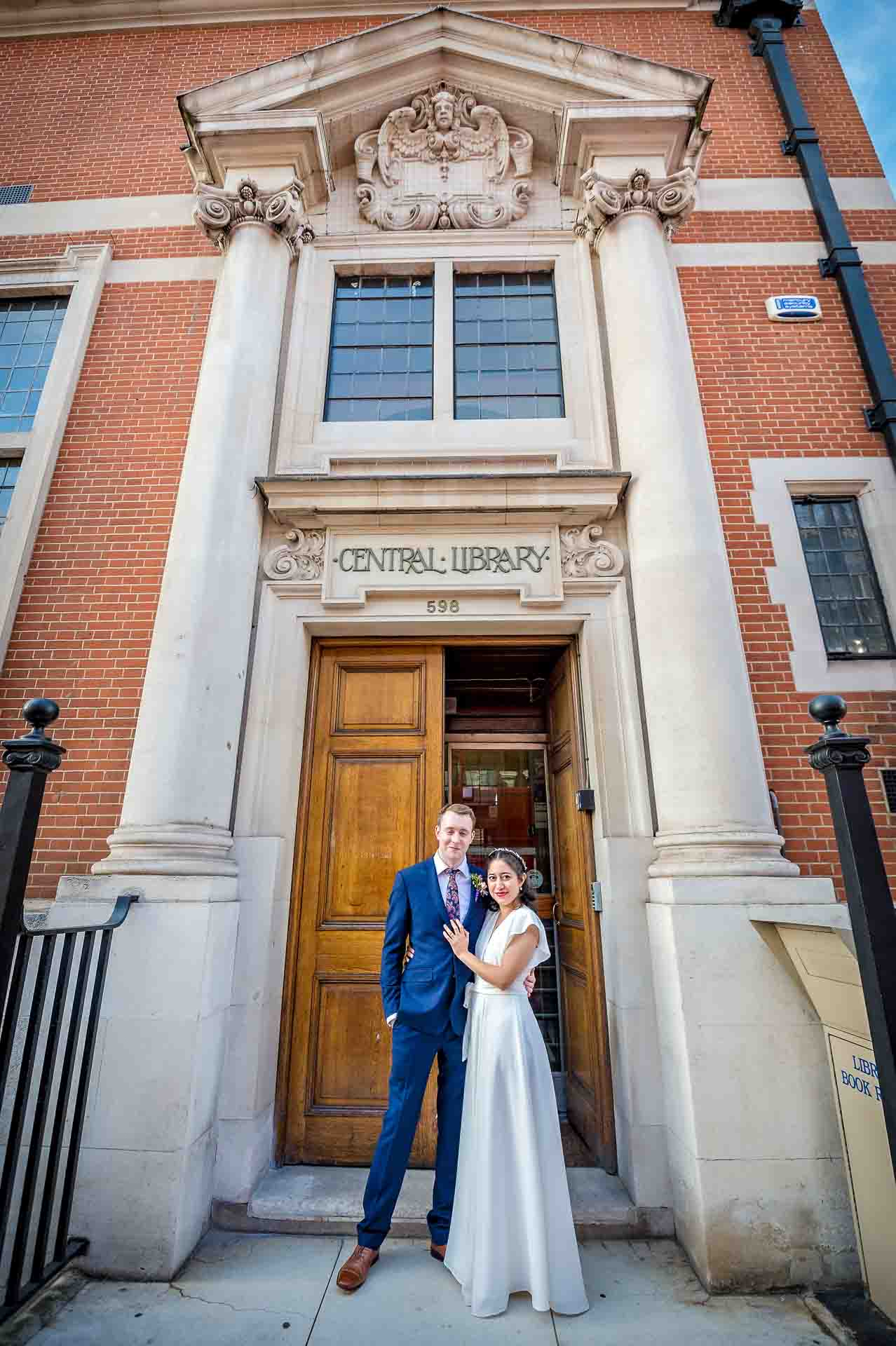Bride and groom posing outside Fulham Library showing the height of the building