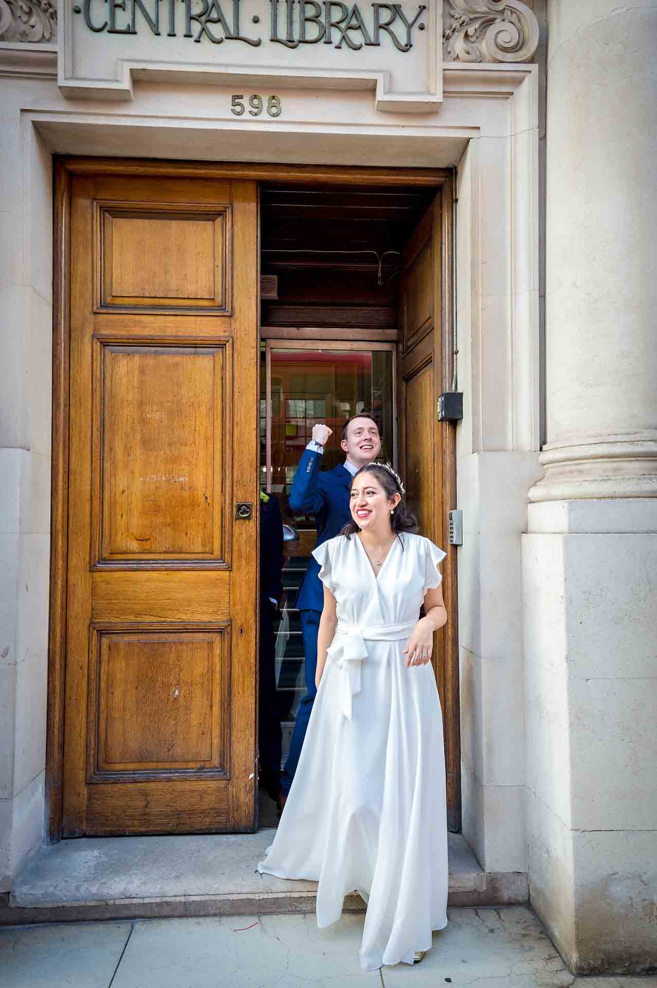 Groom punches the air as he leaves Fulham Library behind bride