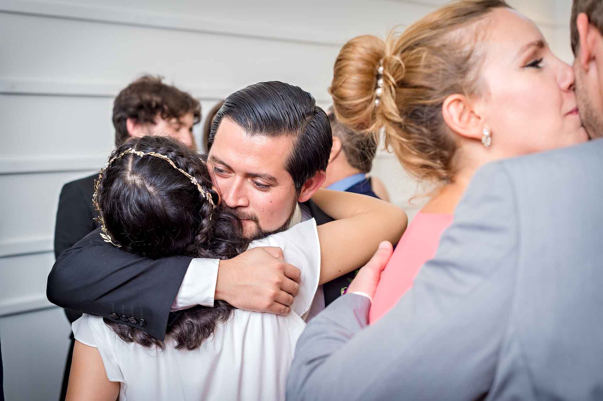 Brother of bride hugs her whilst another couple kiss
