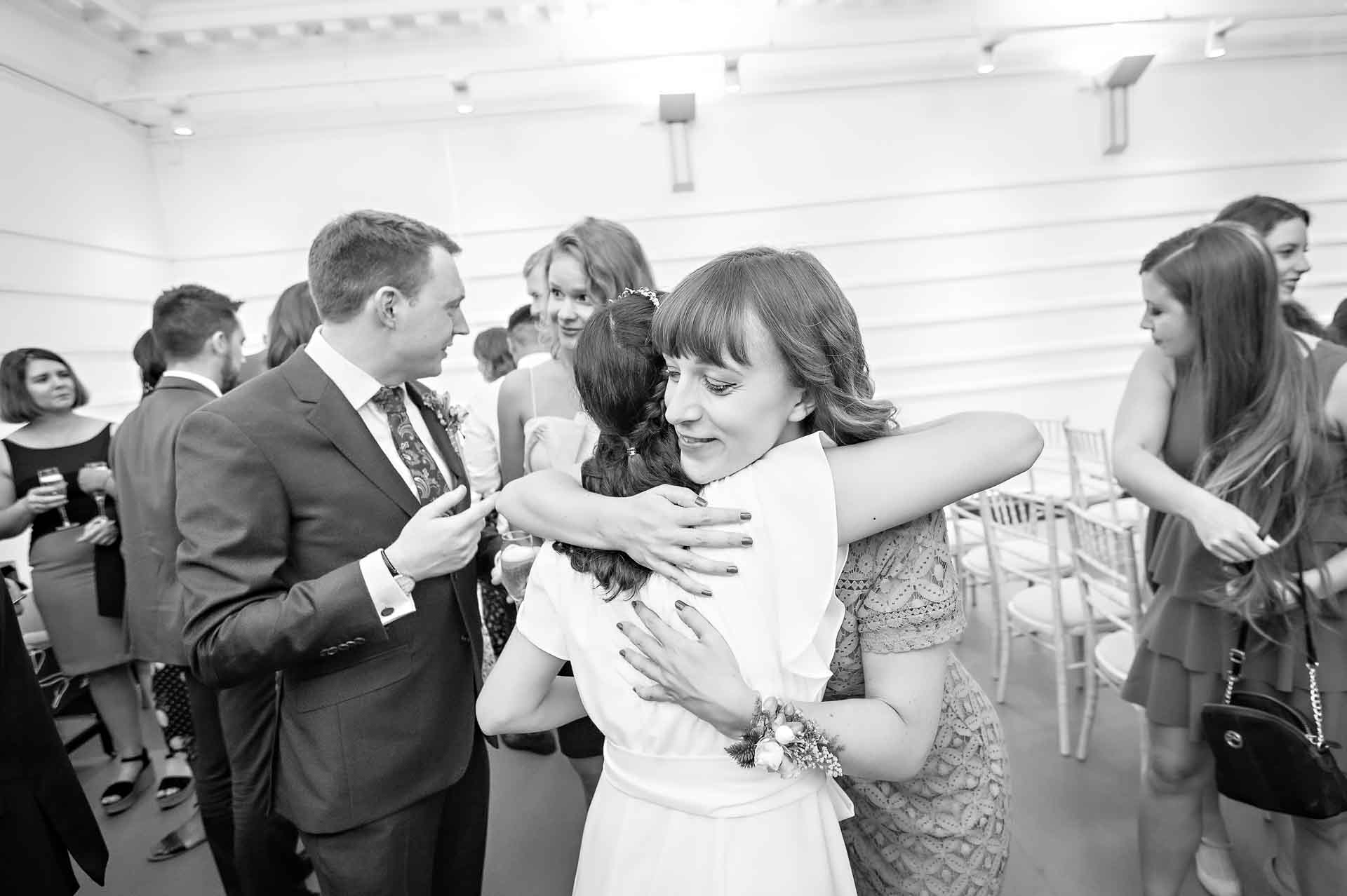 Female friend hugs bride after wedding ceremony