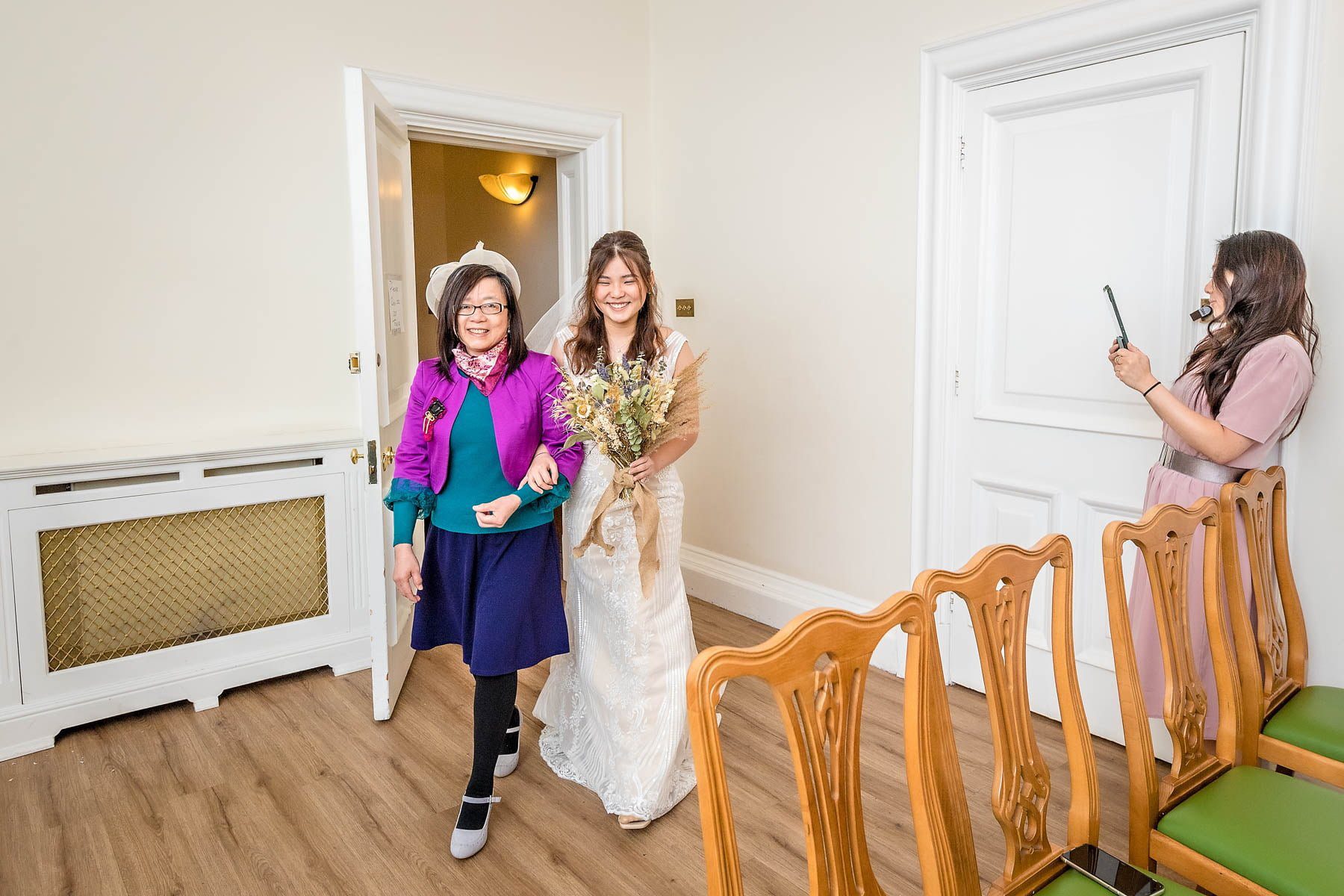 The bride is escorted into the Edwardian Room by her mother for her wedding at Woolwich Register Office