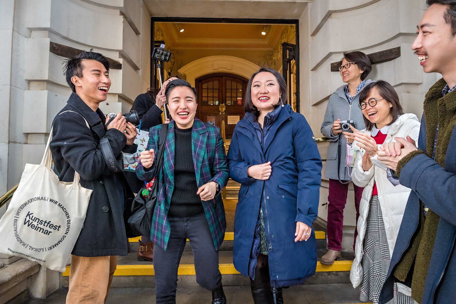 LGBTQ+ couple leaving Greenwich Town Hall as their laughing guests applaud them