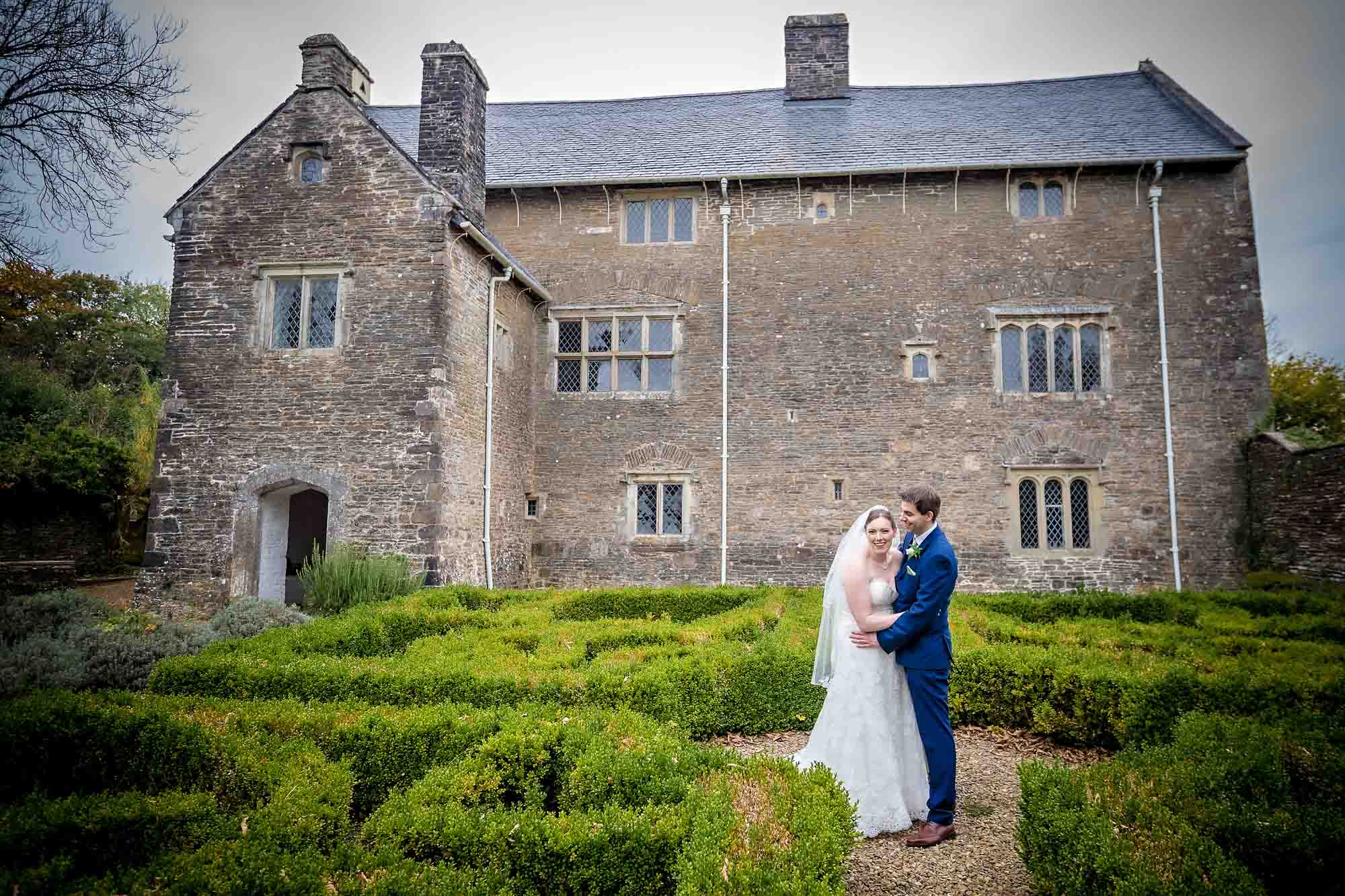 Happy couple in the middle of low hedge at their Llancaiach Fawr Manor wedding
