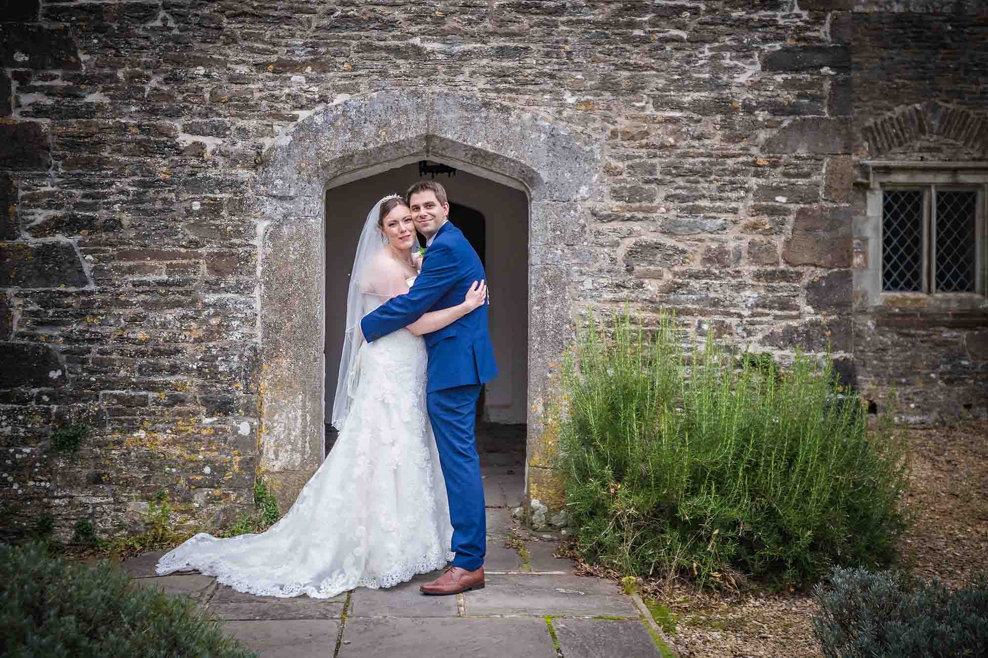 Bride and groom holding each other in front of the old entrance to Llancaiach Fawr Manor at their wedding