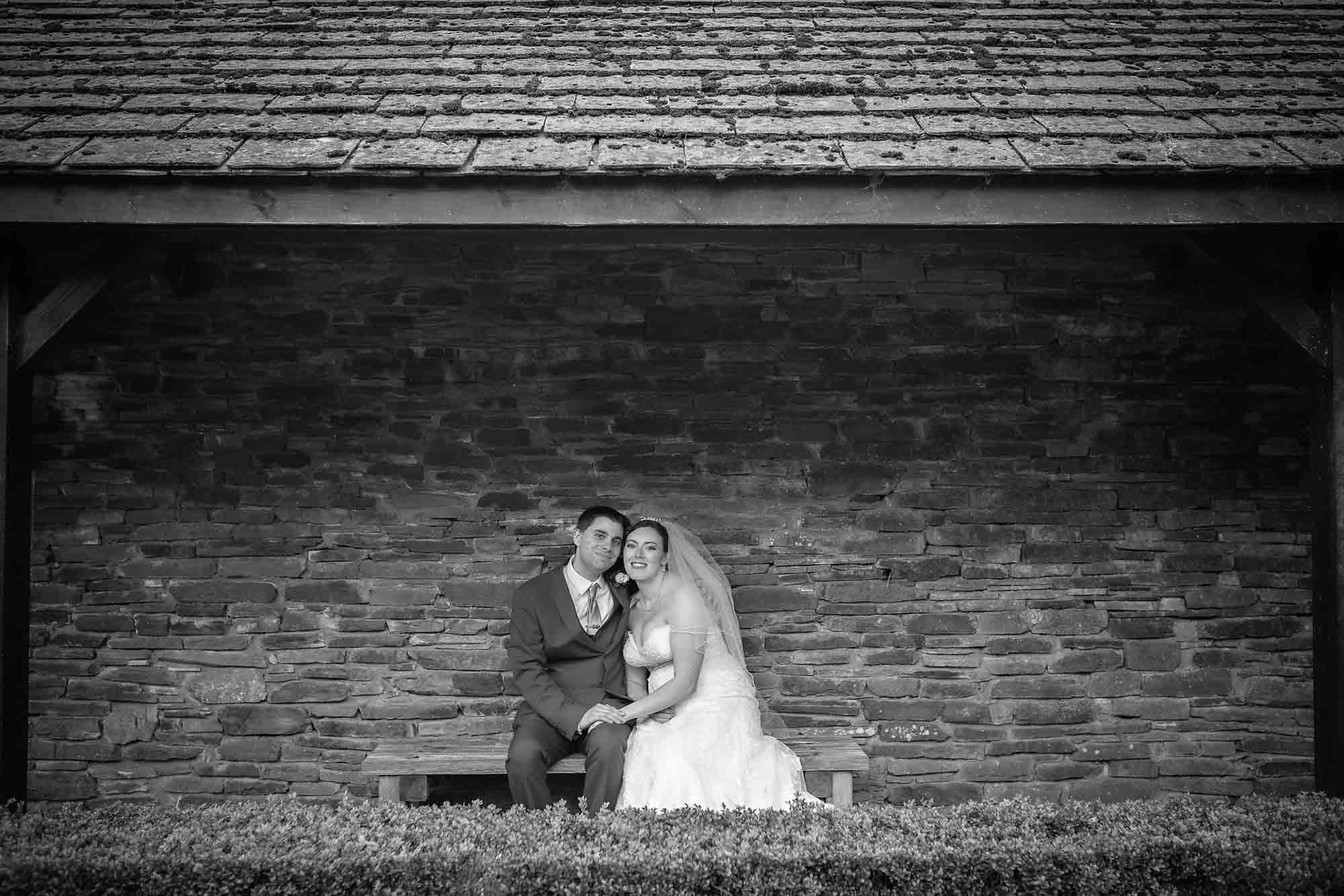 Newly-weds sitting under old shelter at their wedding in Llancaiach Fawr Manor