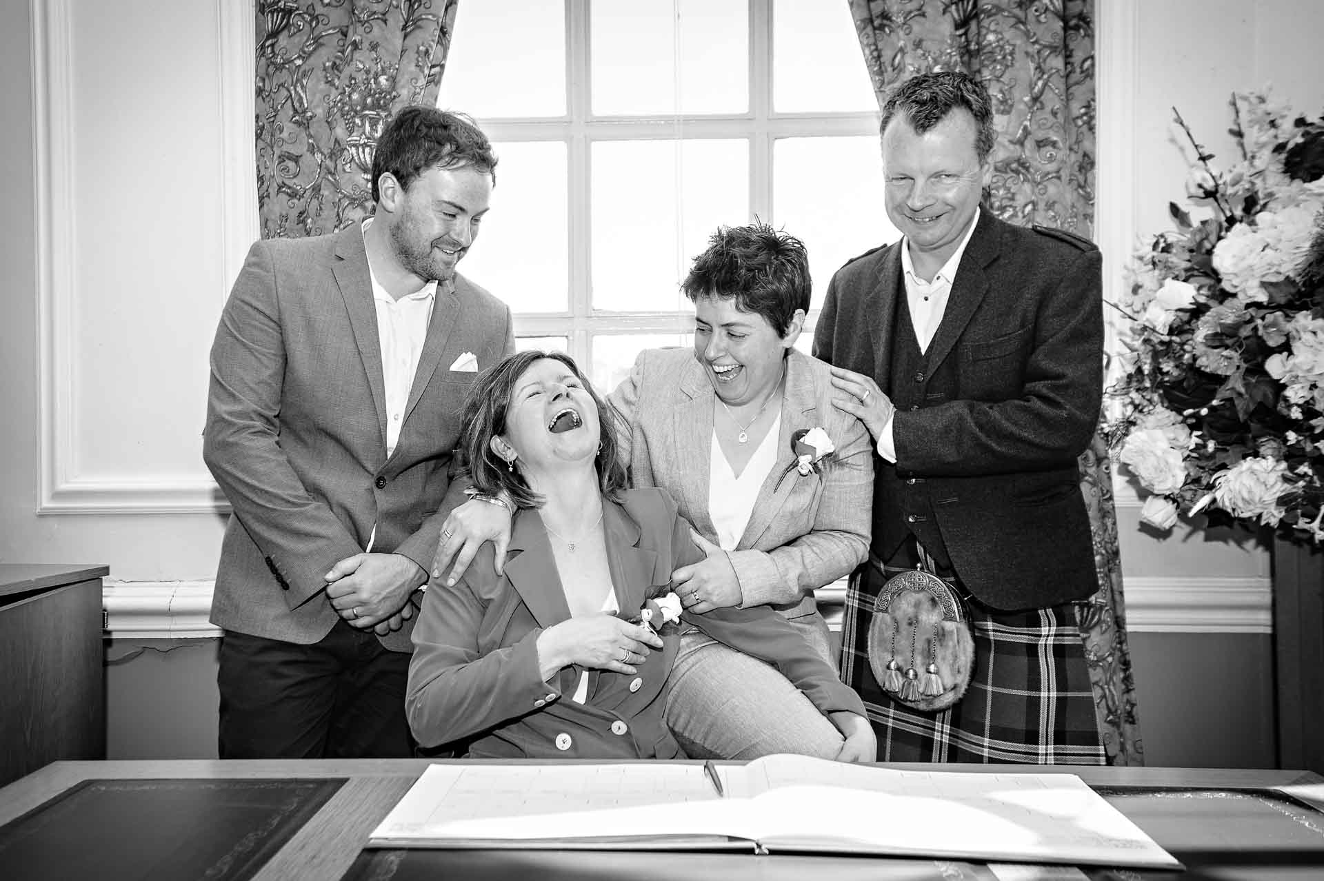 Group photo with register - same sex wedding bride laughing with guests