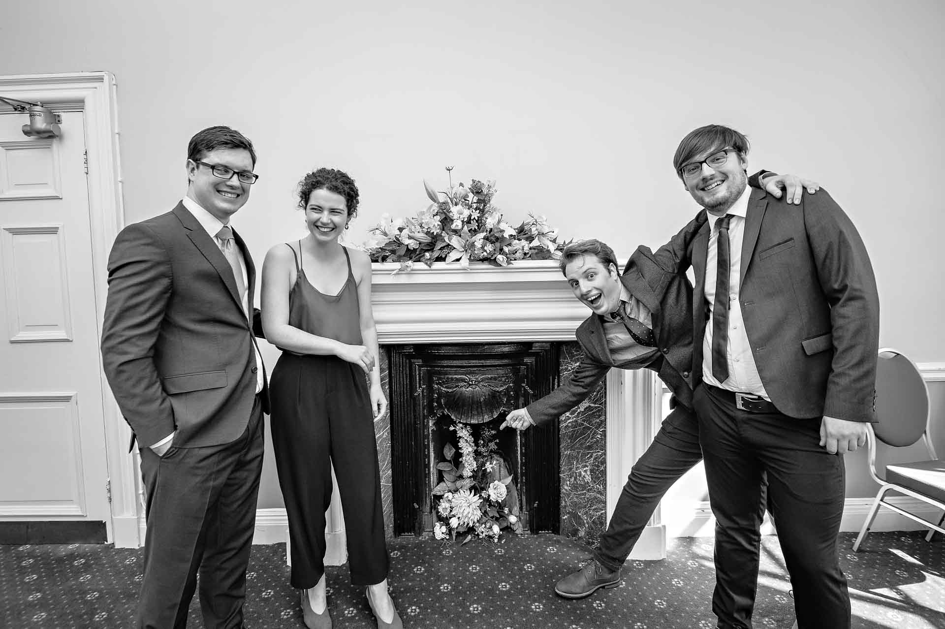 Four guests larking about in front of fire place at Cardiff City Hall wedding