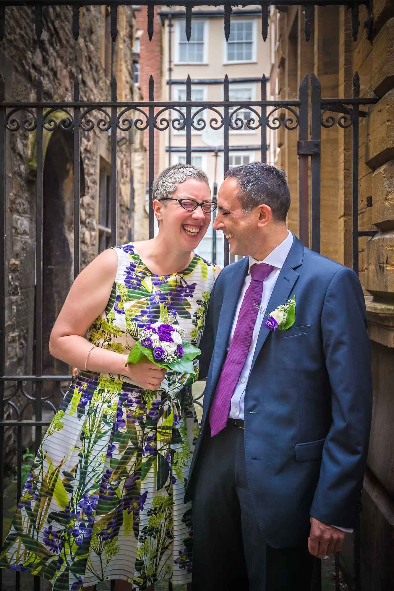 Newly-weds laughing in front of gates in Bristol.