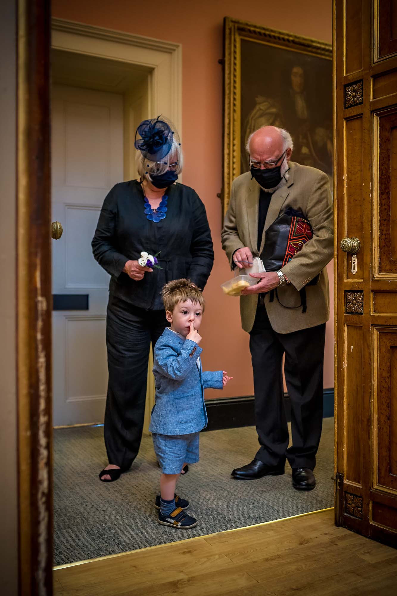 Boy with finger on face looks into Lantern Room whilst masked grandparents watch on in Bristol
