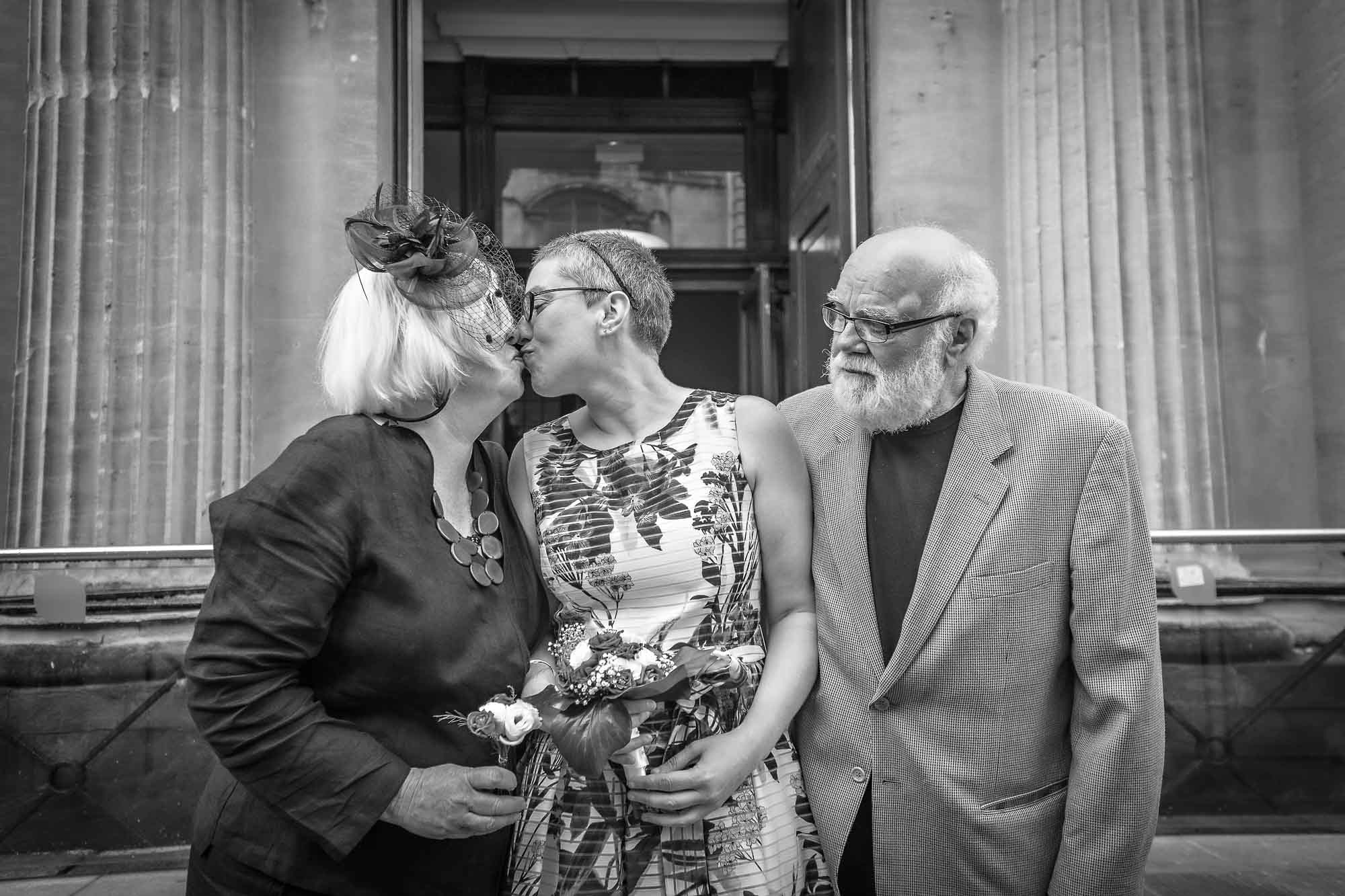 Bride and mum kiss whilst dad looks on at Bristol wedding
