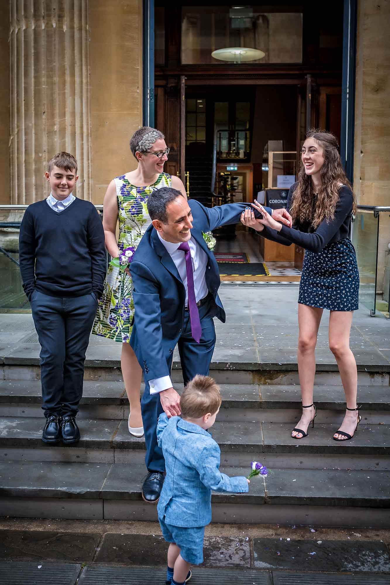Groom's son pulls him over on steps outside Bristol Register Office during posed wedding photos
