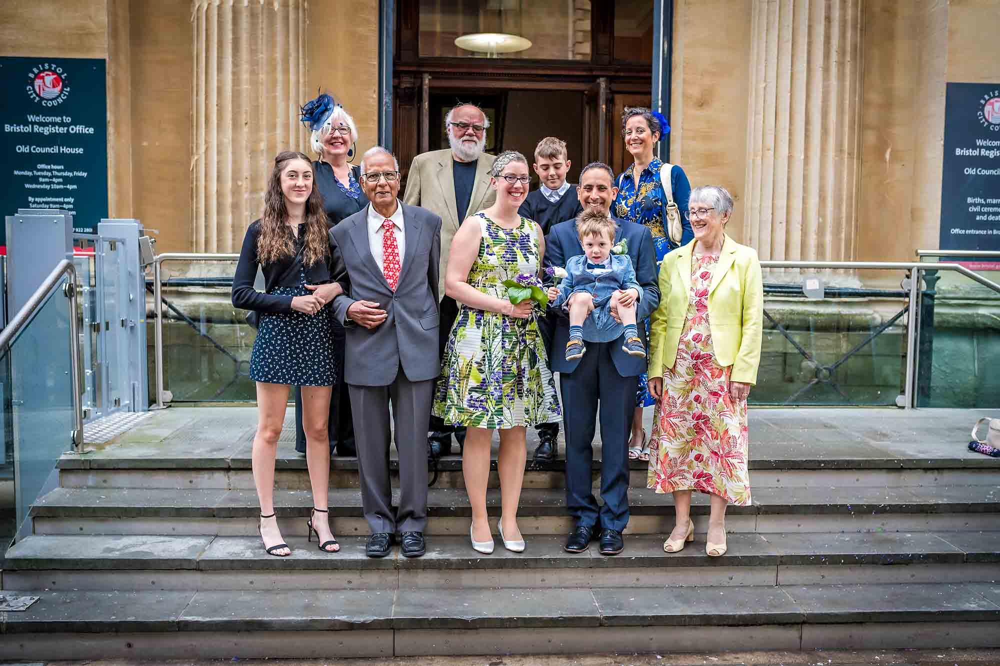 Portrait of whole family including little boy being held outside Bristol Register Office