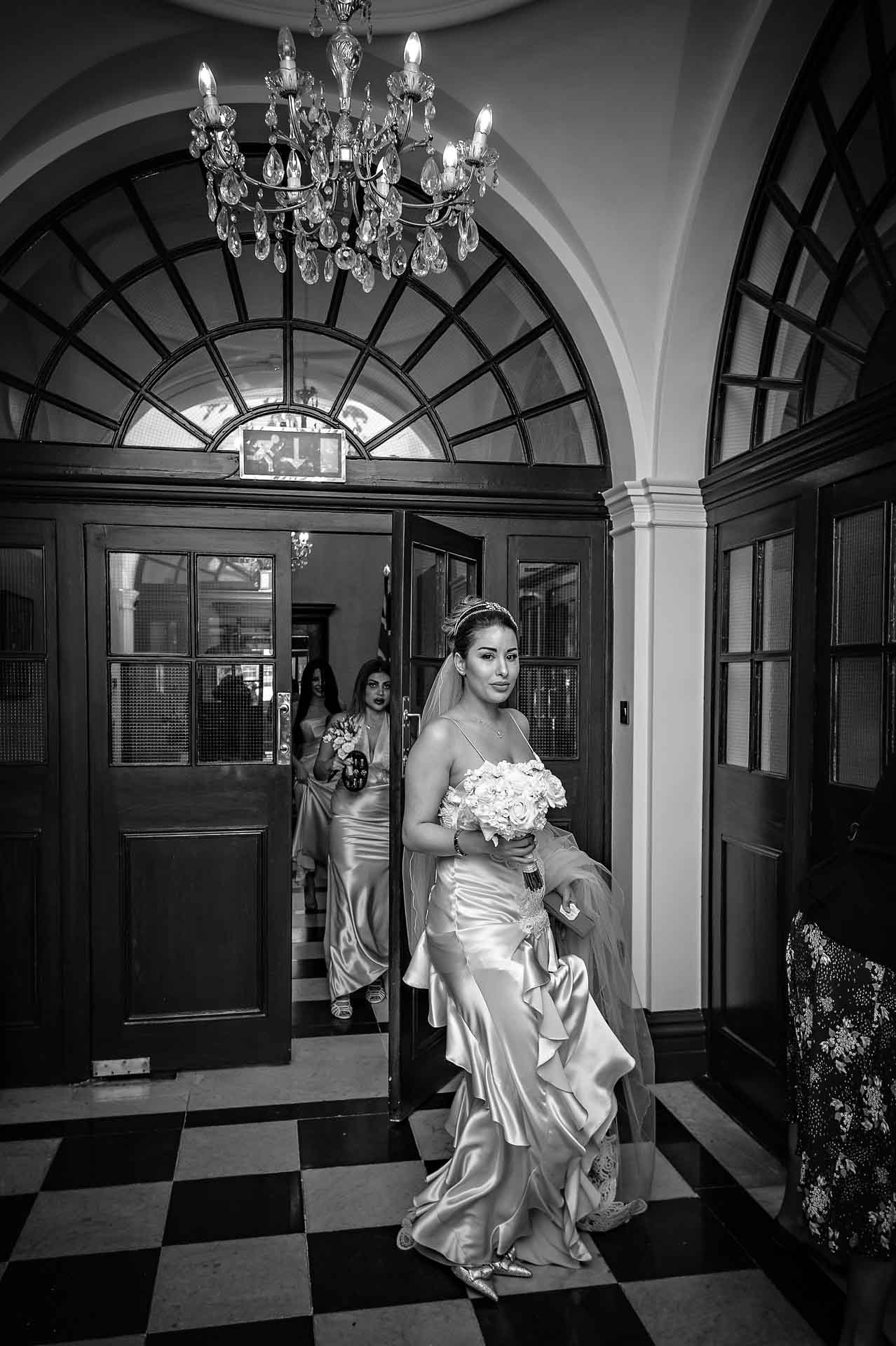 The bridal party arrive in the entrance hall of Chelsea Old Town Hall