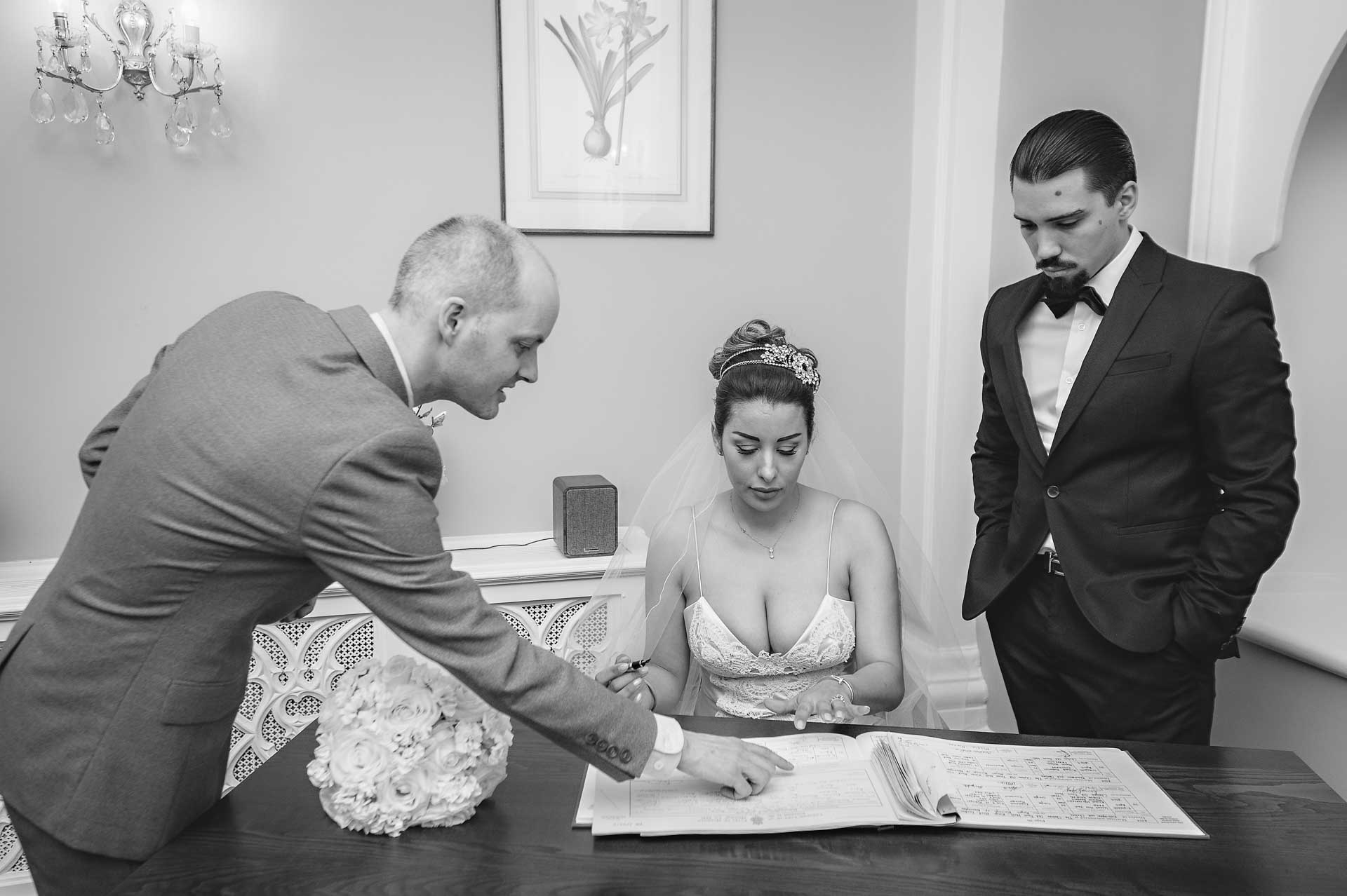 The registrar points out where the bride needs to sign at a London wedding
