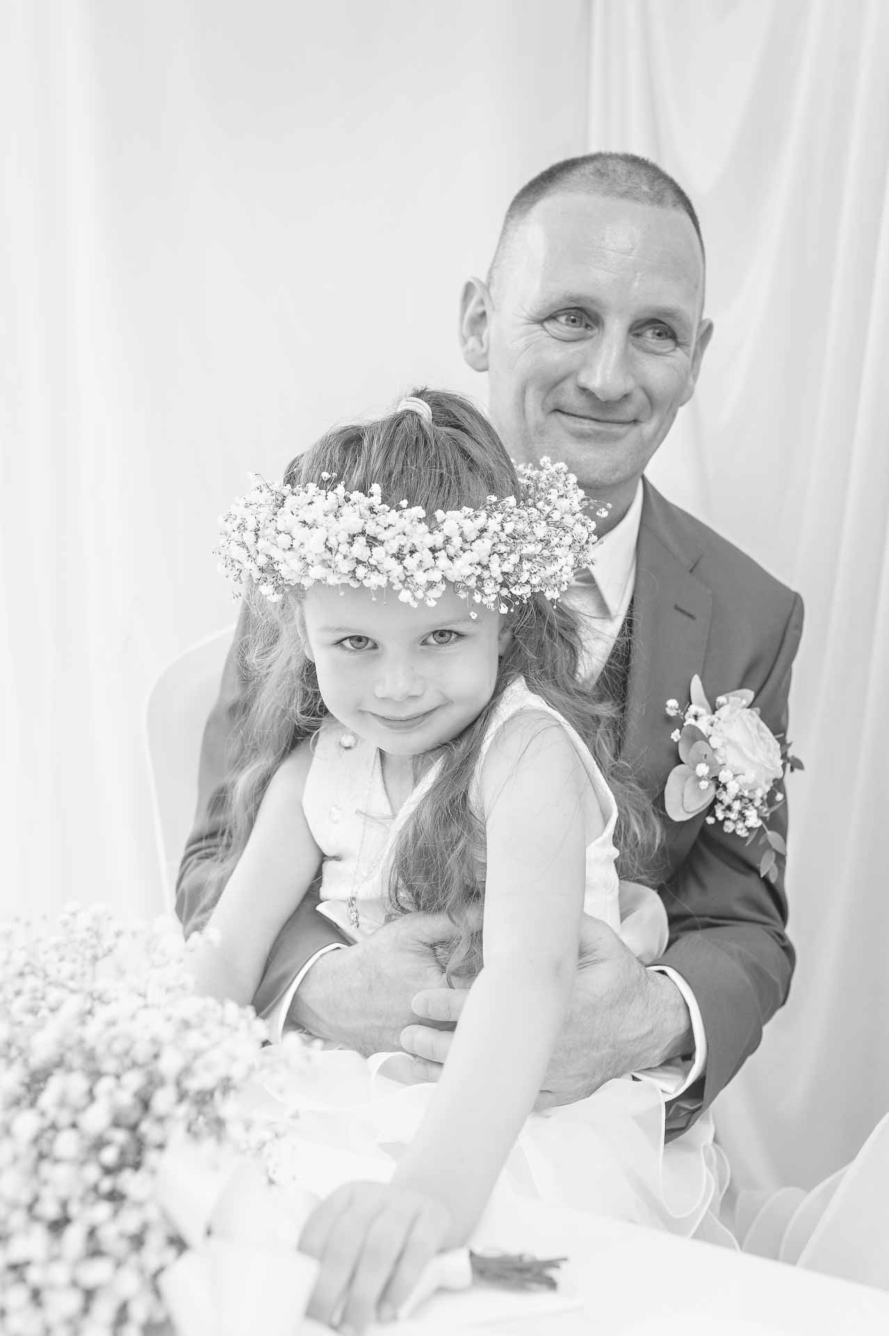 Father with young daughter on his knee at wedding in South Wales