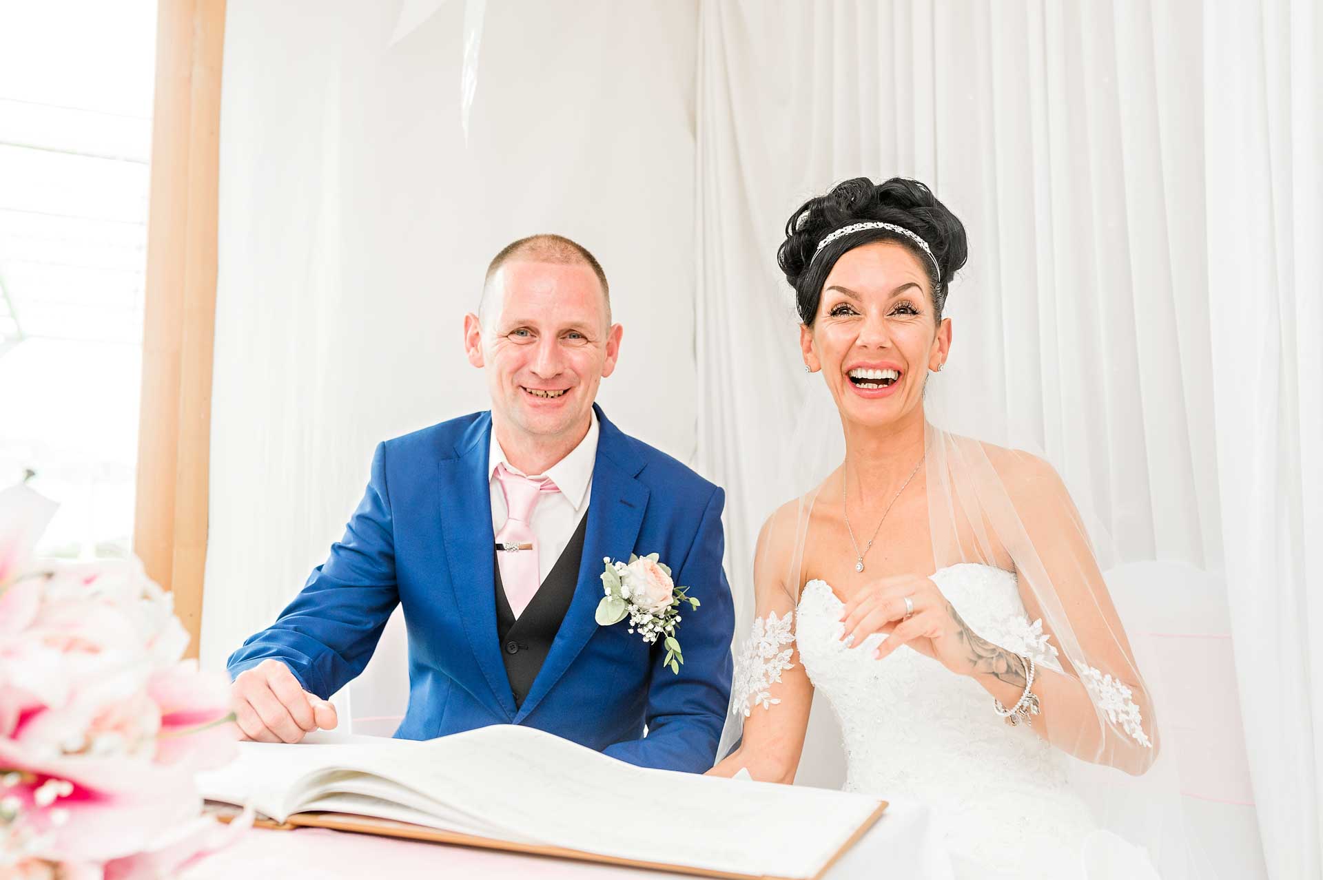 The couple laughing with the wedding register in the Marquee at Ridgeway Golf Club, Caerphilly