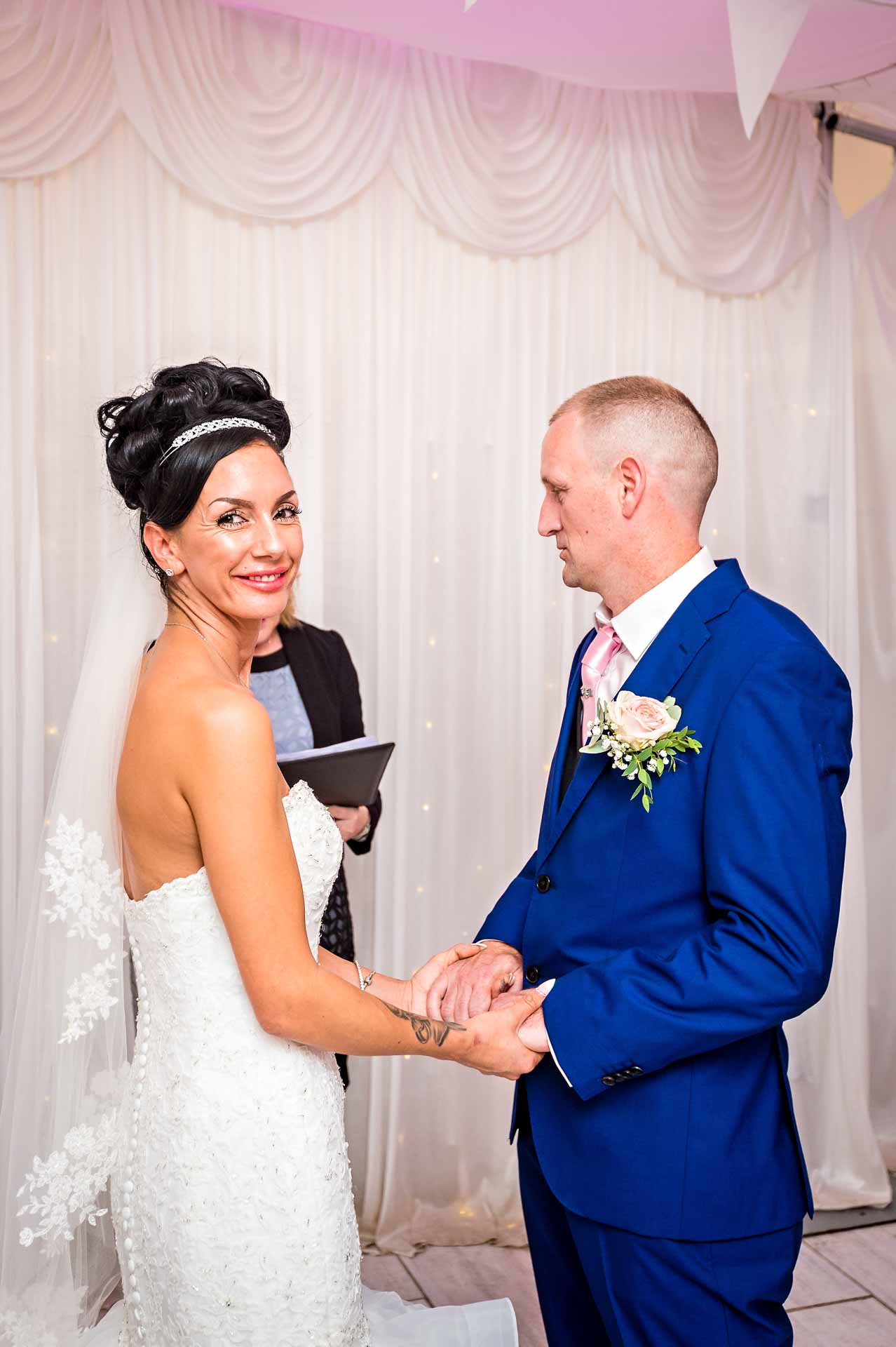 The bride looking at the camera whilst the groom looks at the registrar at Caerphilly wedding