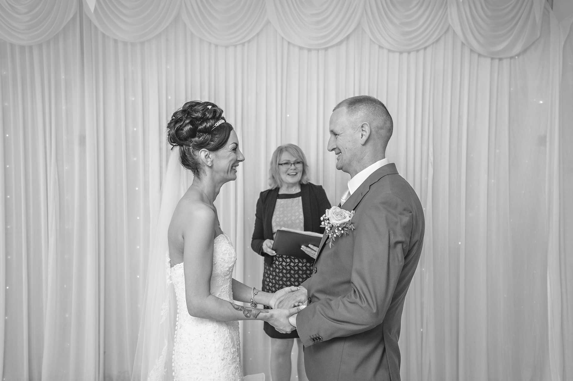 The bride and groom holding hands whilst looking at each other in the Marquee at Ridgeway Golf Club