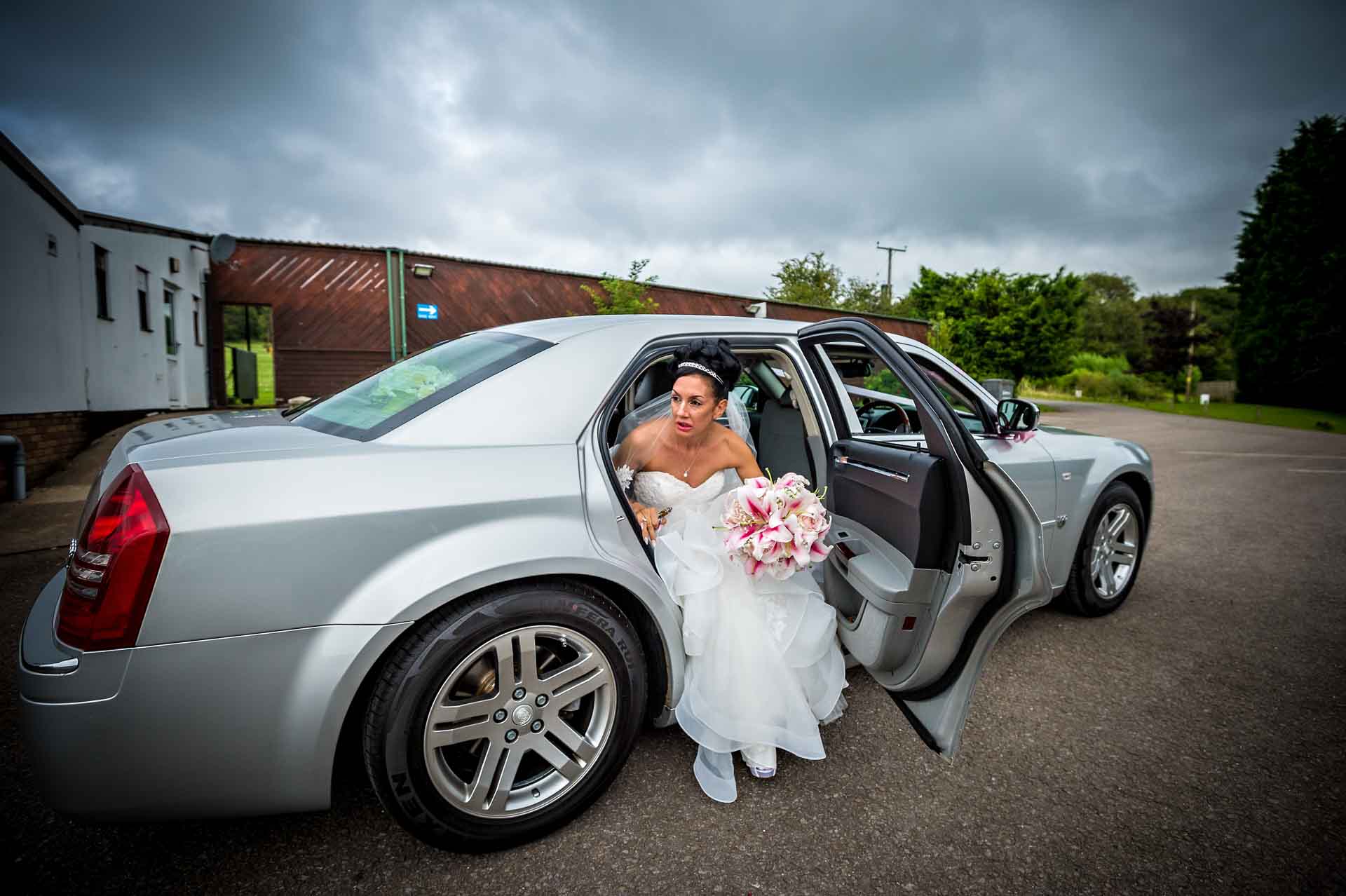The bride arrives and gets out of a silver car at the Ridgeway Golf Club in Caerphilly