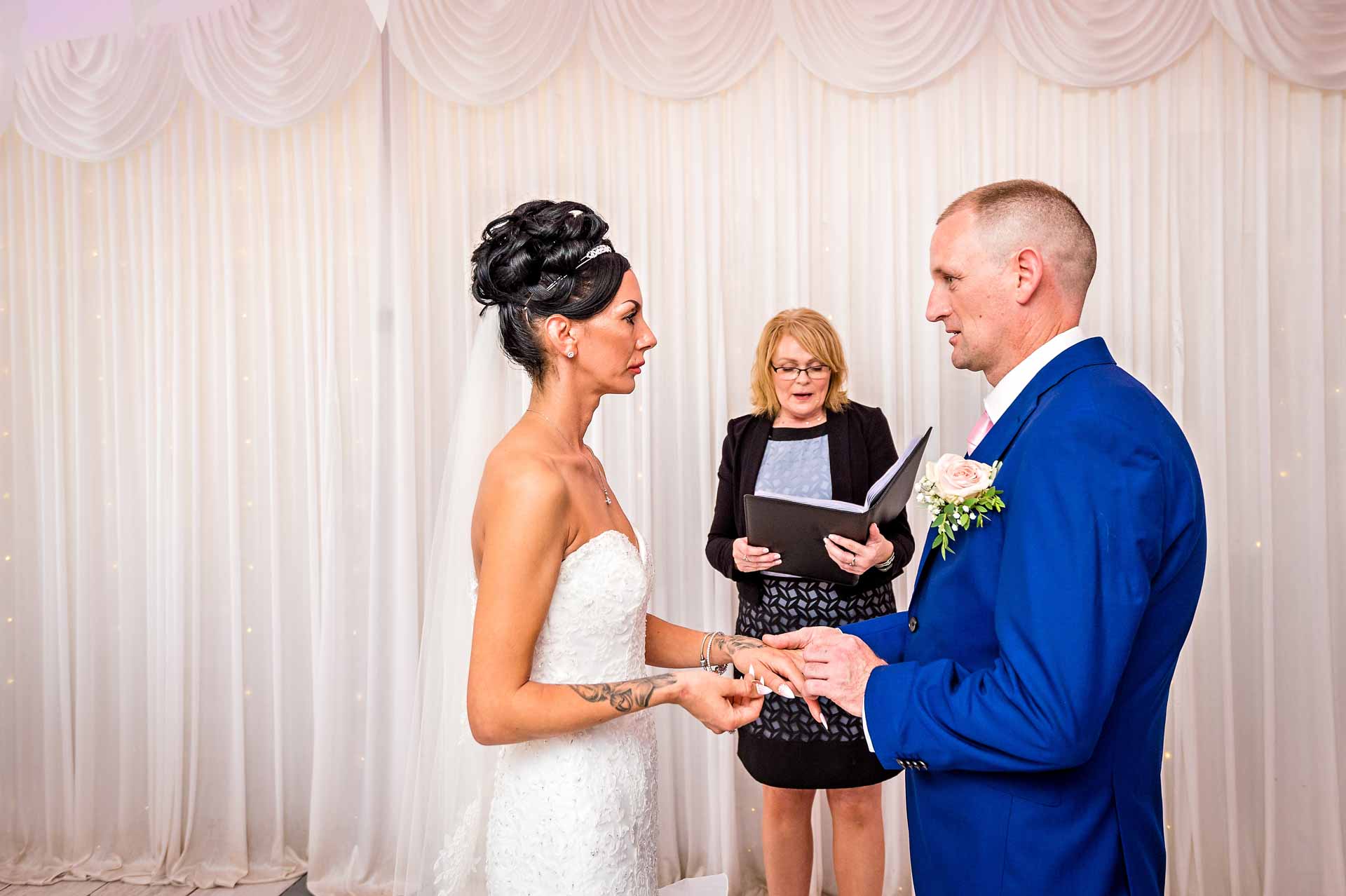 Groom places the ring on his bride's finger in Caerphilly